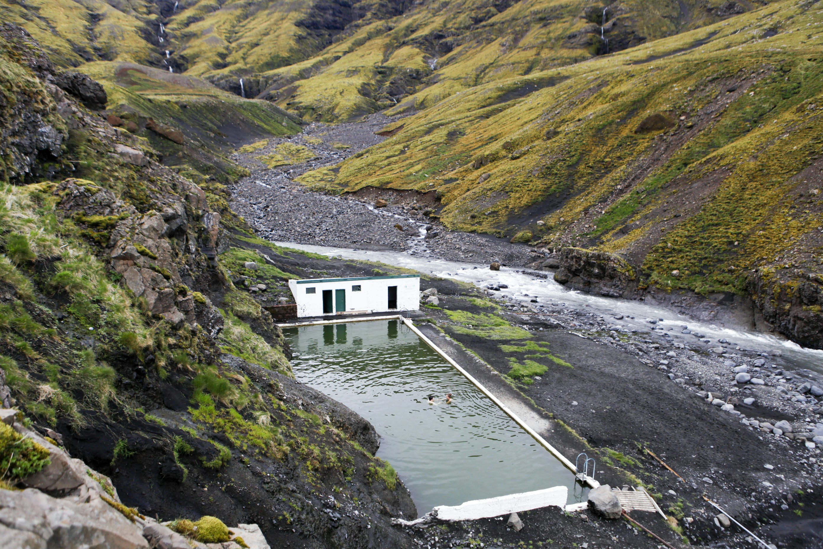 Seljavallalaug in Southwest Iceland, Iceland's oldest still-standing pool, surrounded by green mountains on both sides.