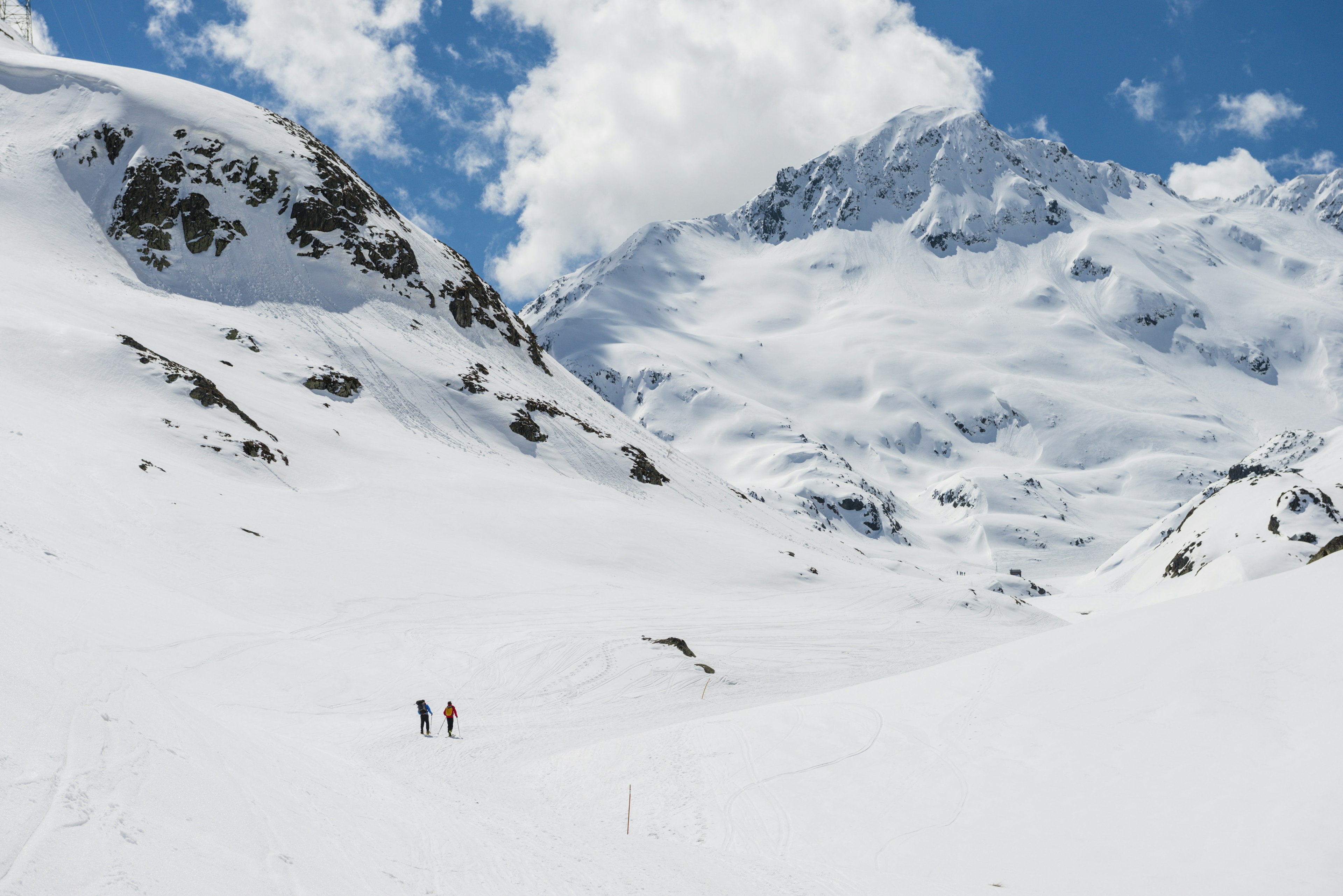 Two people hike through a snowy mountain landscape