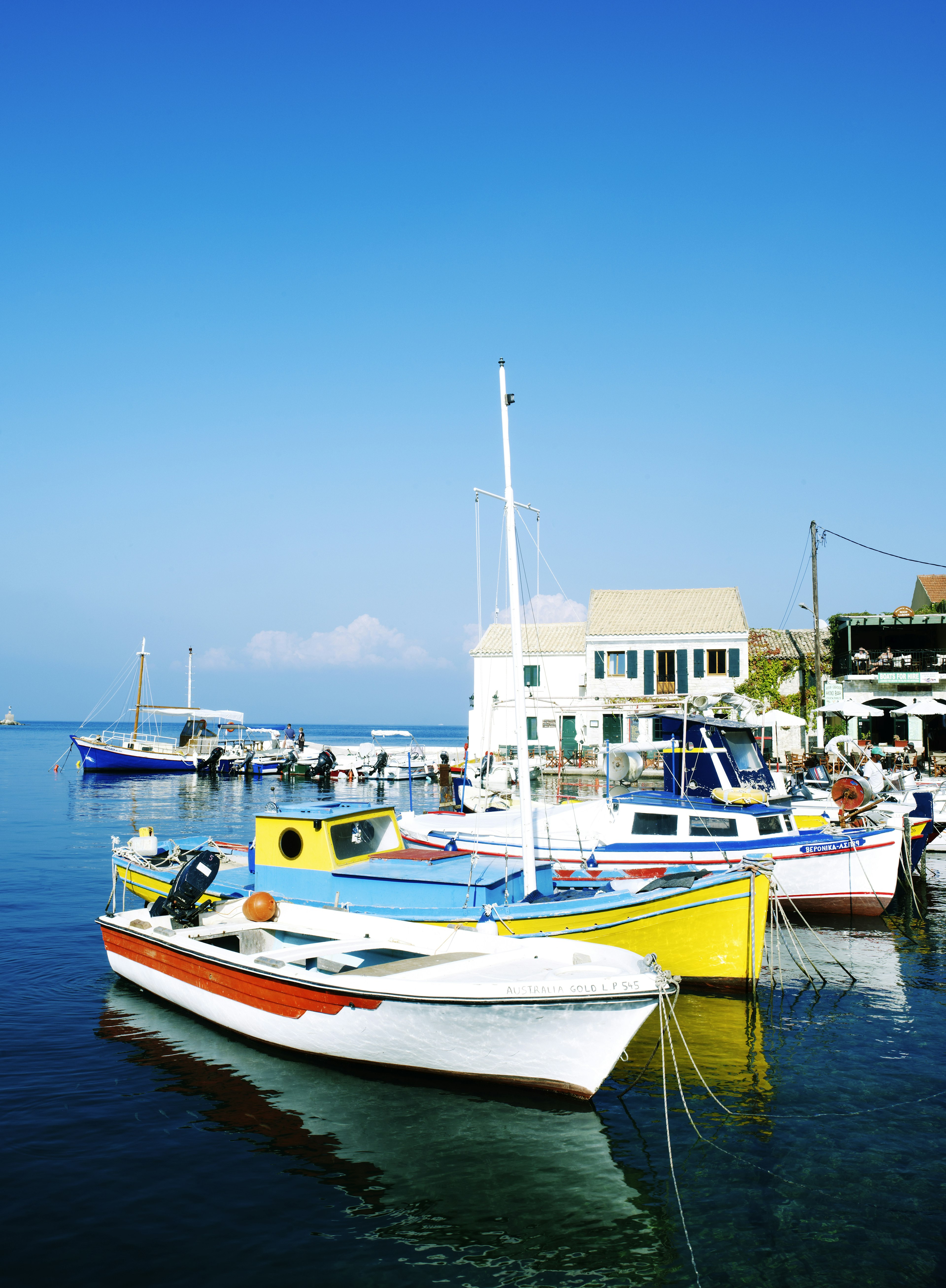 Several brightly coloured fishing boats are docked together in a small harbour.