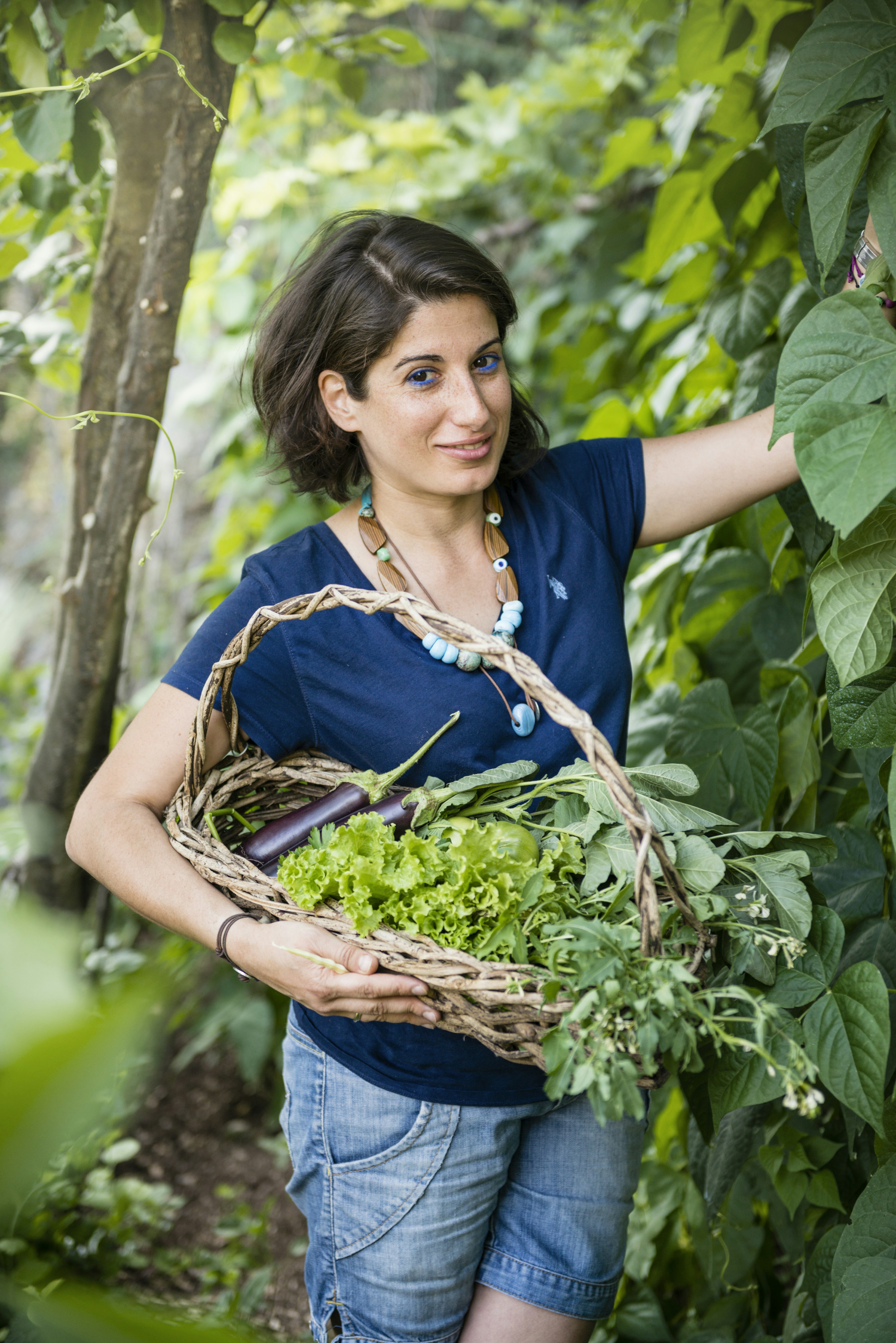 Young woman collecting herbs and vegetables from her kitchen garden.