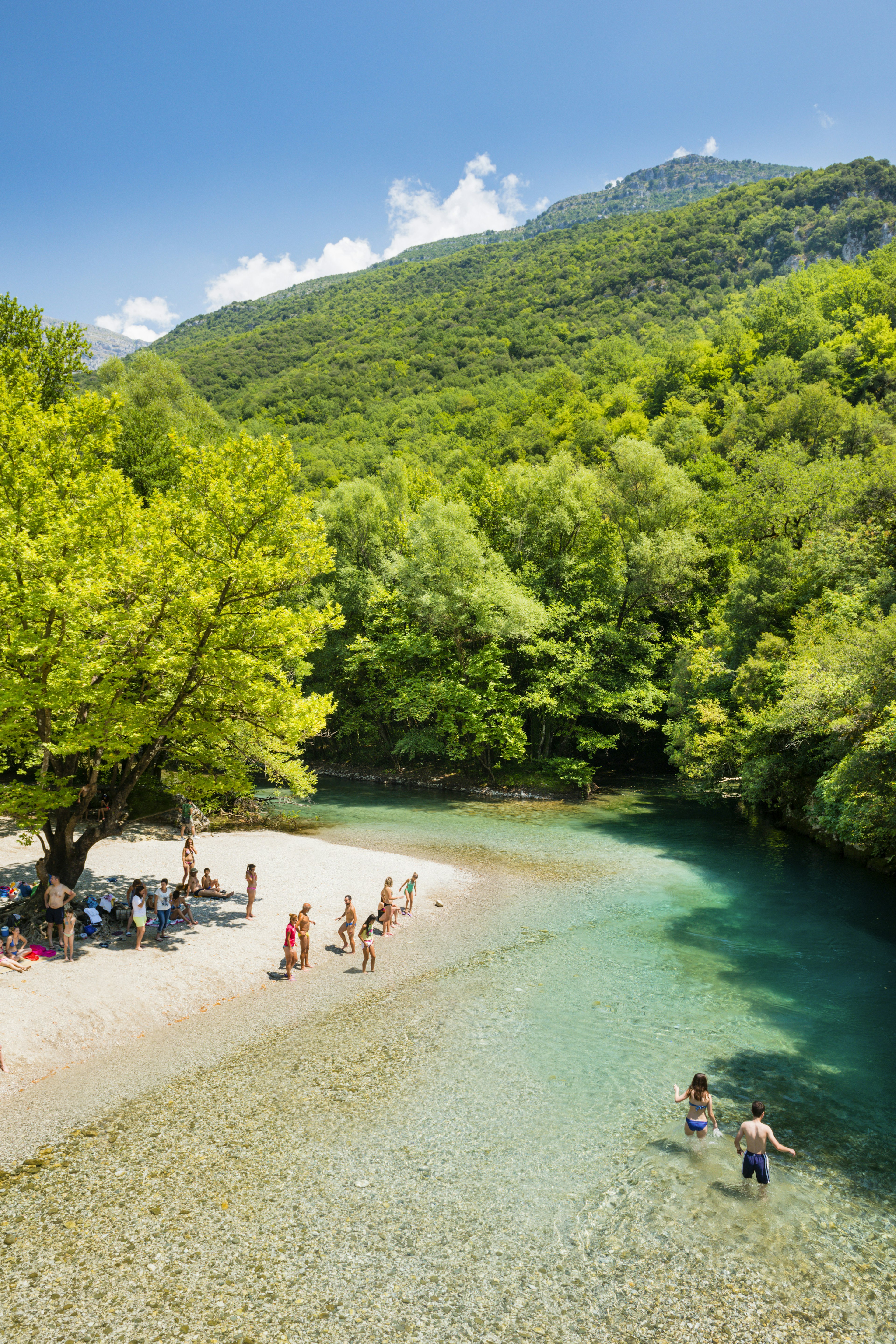 Swimmers and bathers on beach banks of bend in the Voïdomatis River near the Aristi Bridge.