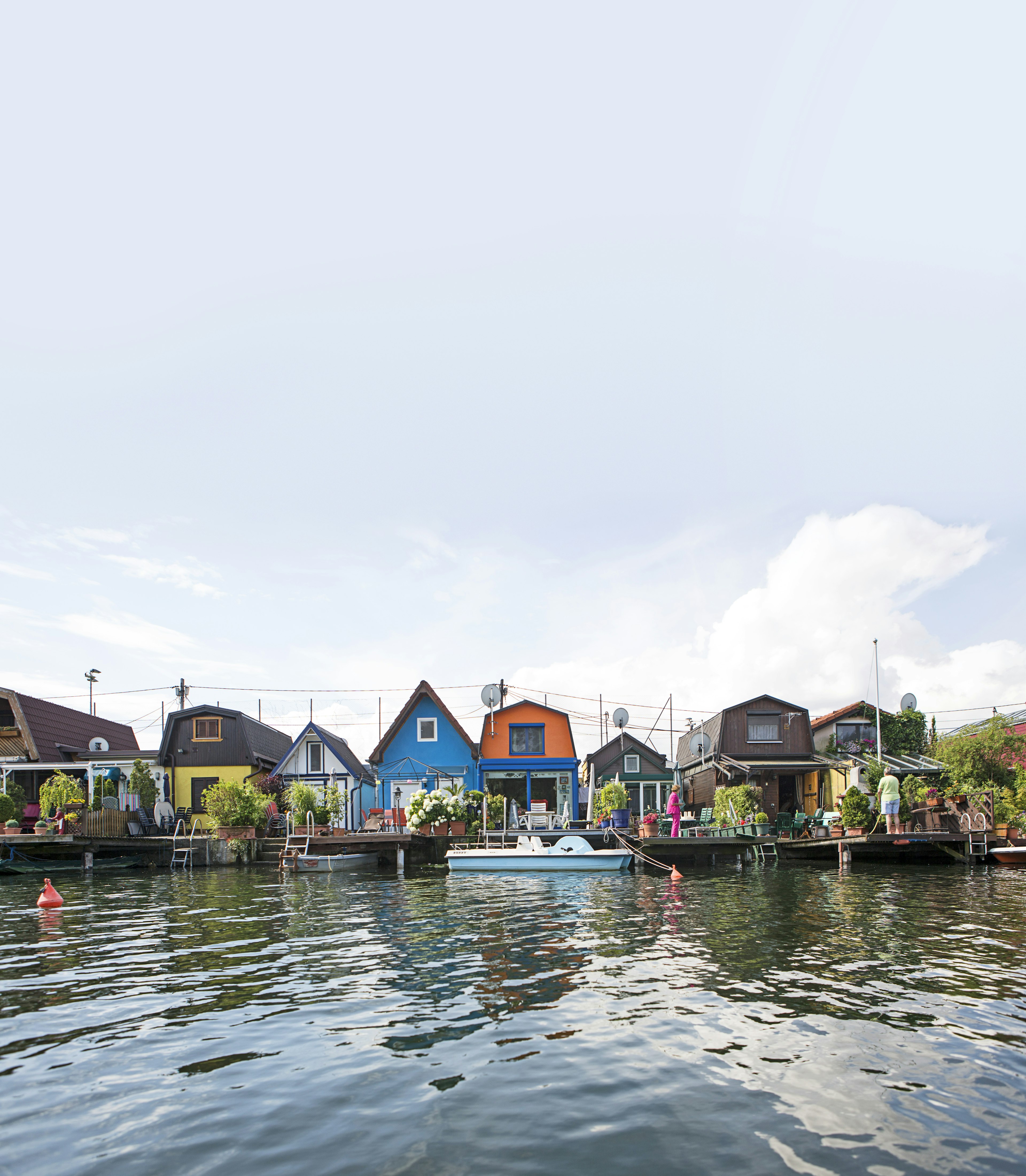 Small boats are moored to the back gardens of colourful lakeside houses at Dampfschiffhaufen.