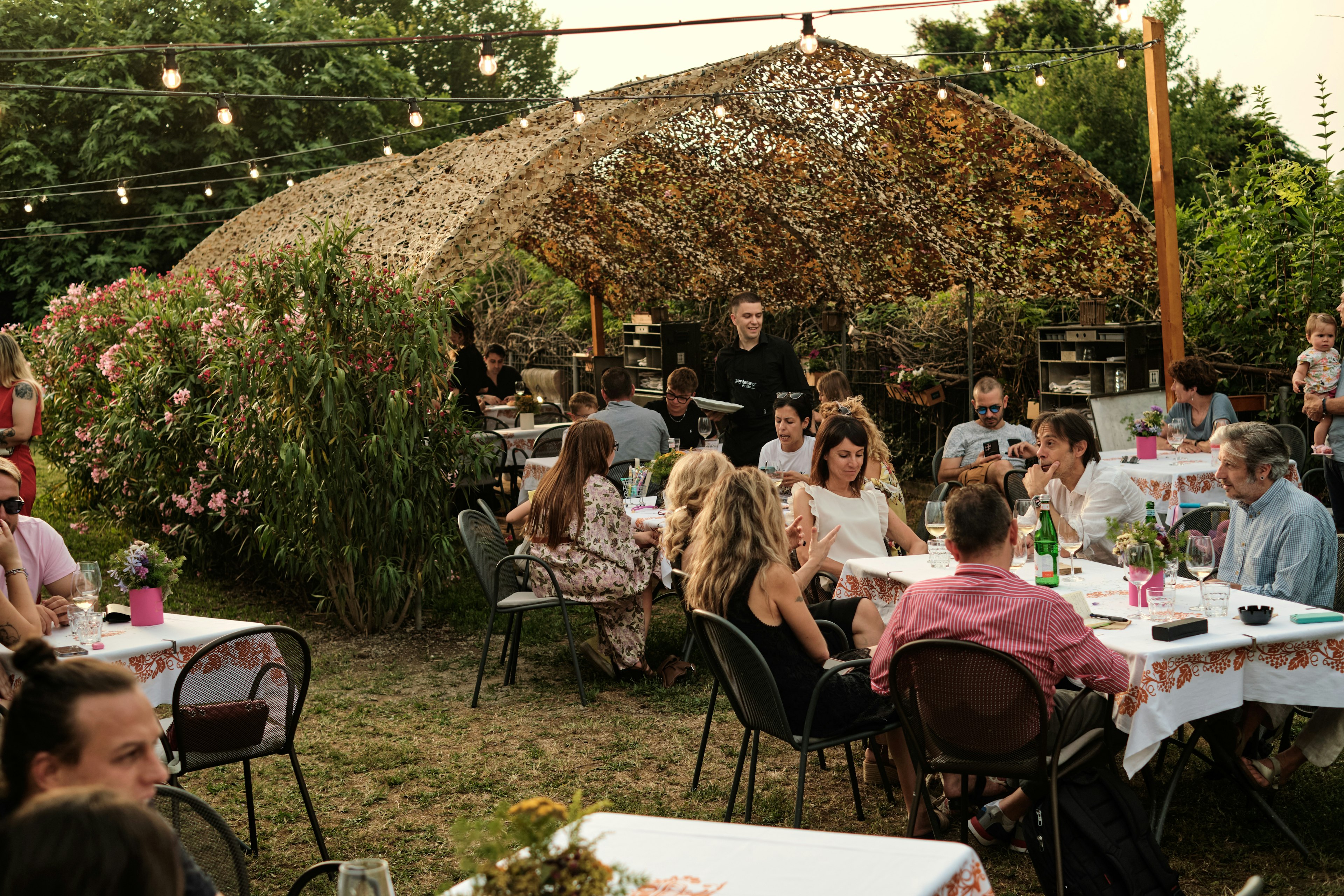 People sitting at outdoor tables in a former greenhouse turned restaurant.