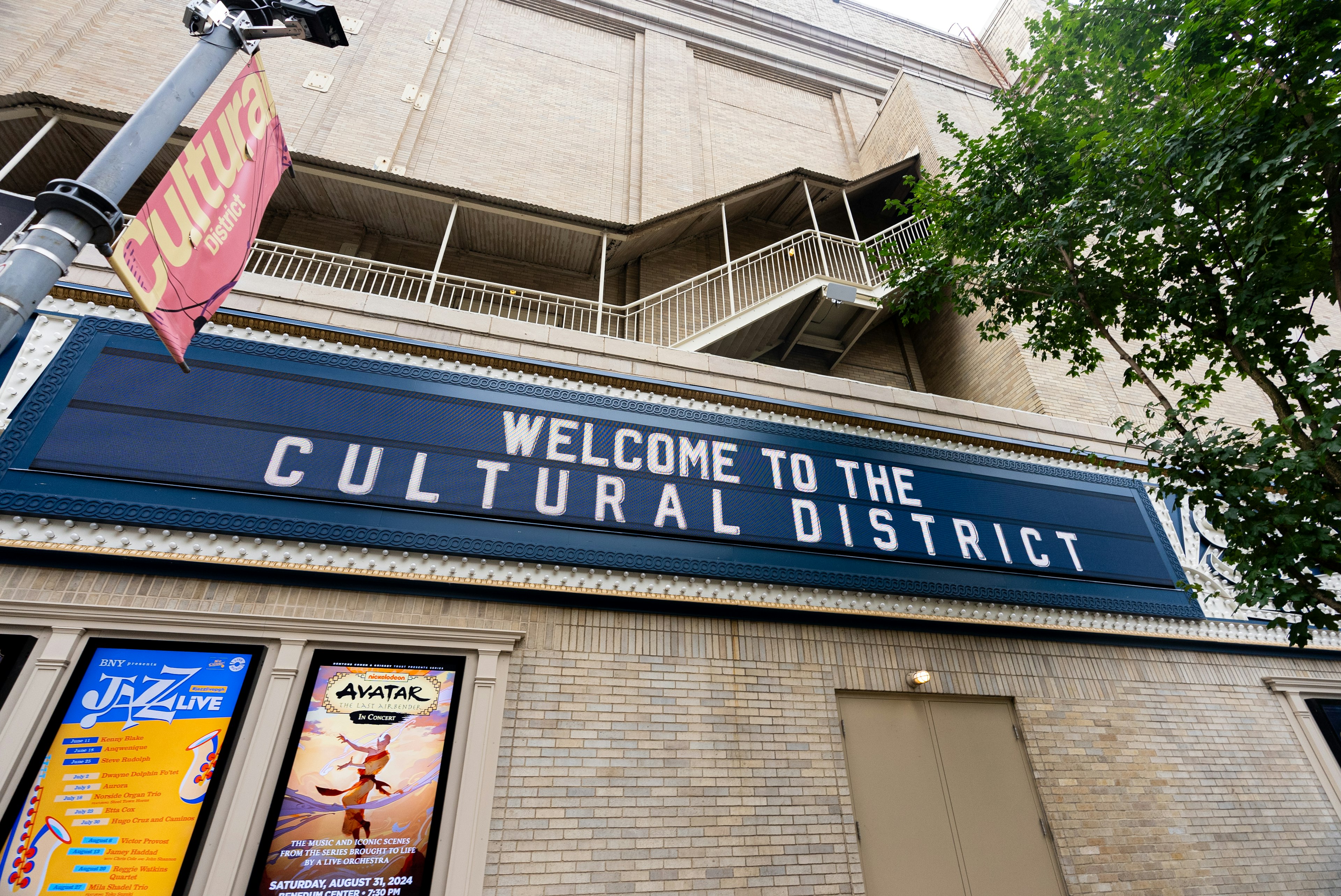 A theater in Pittsburgh has a blue sign that says Welcome to the Cultural District