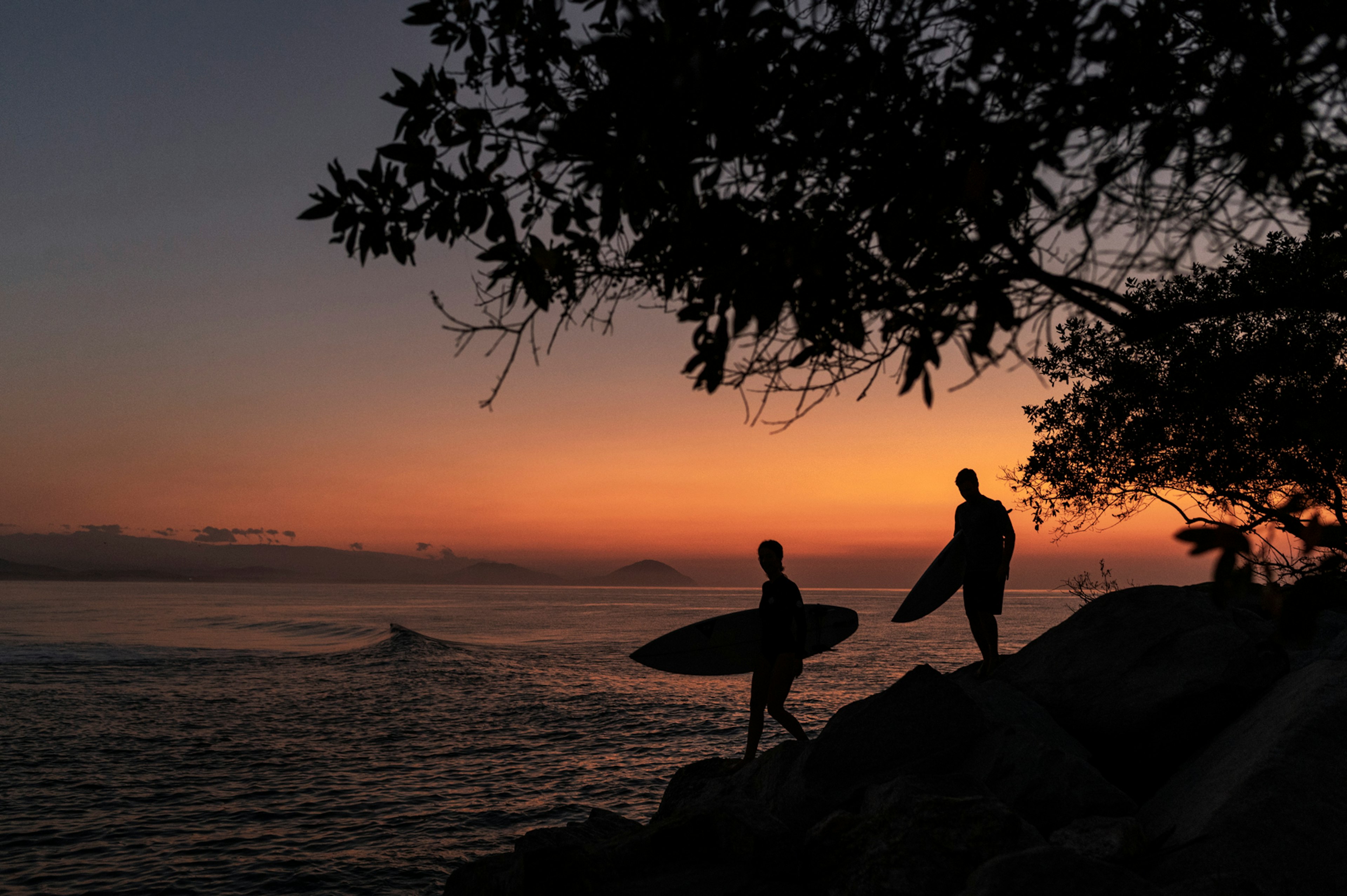 Two surfers head to the ocean at sunset in Mexico