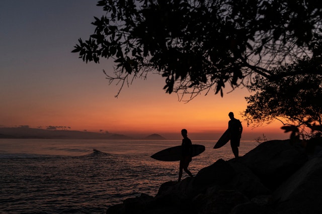 Two surfers head to the ocean at sunset in Mexico