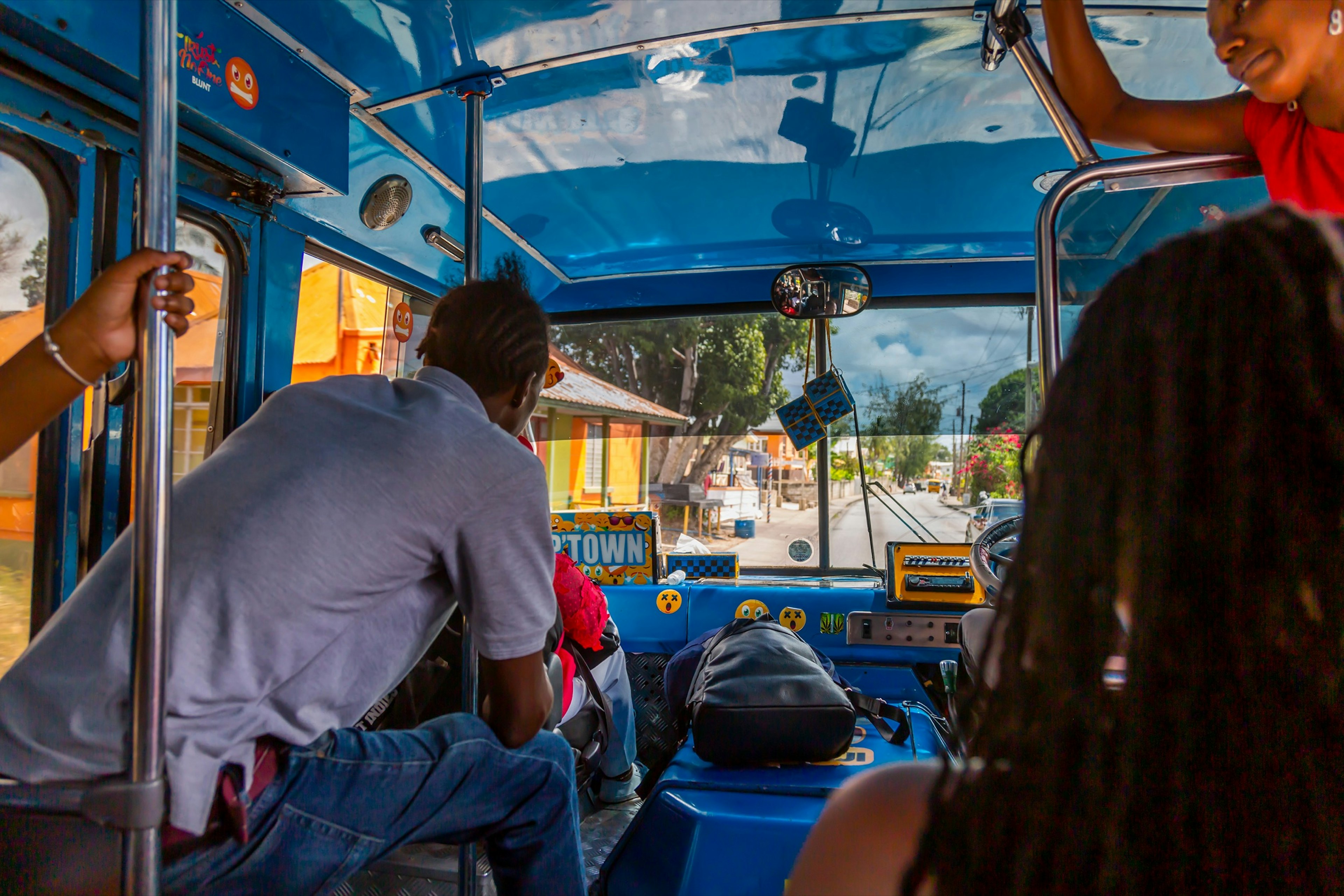 Shot from inside of a Reggae Reggae bus looking through the windshield. There are people sitting around the bus.