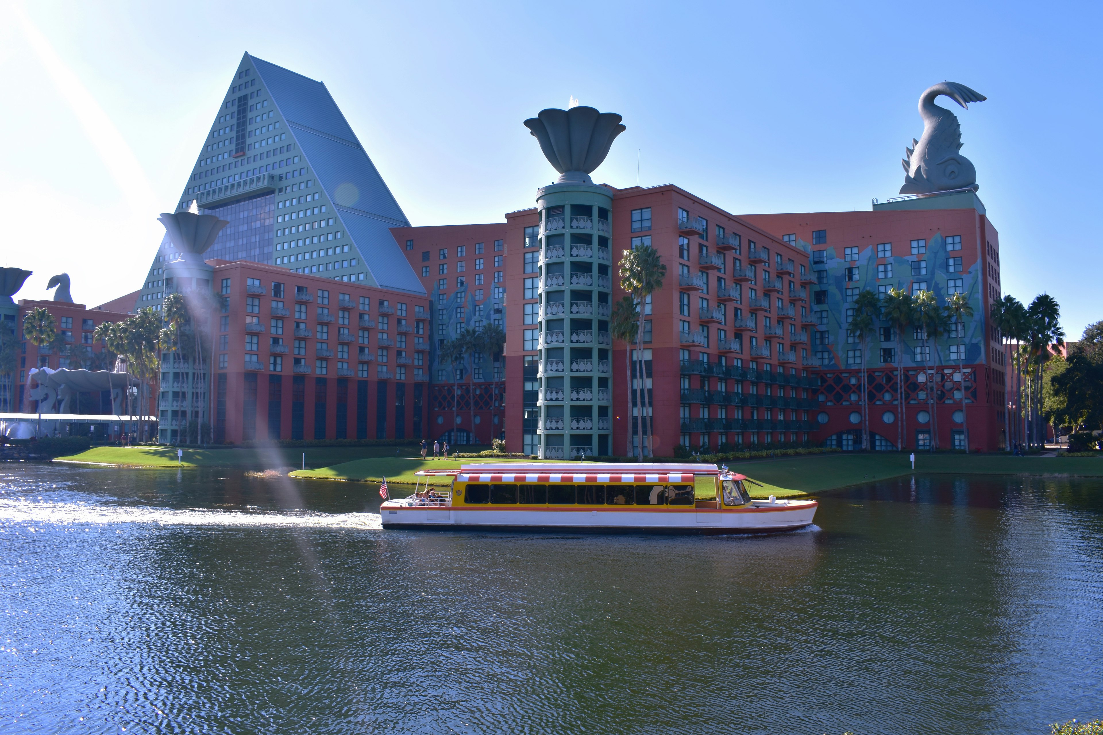 A boat at Disney World cruises past the Dolphin and Swan Resort