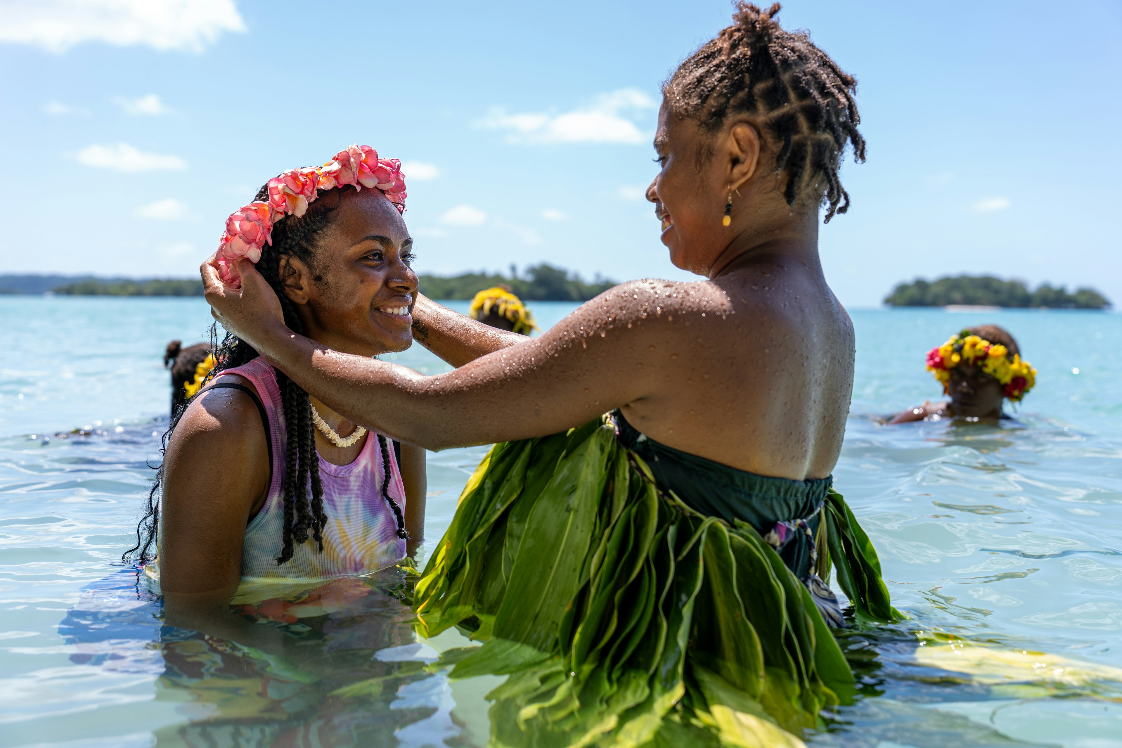 A tourist is presented a headband of flowers from a young woman from the Banks Islands in traditional dress after showing her how to perform one of their “water music” songs in Vanuatu