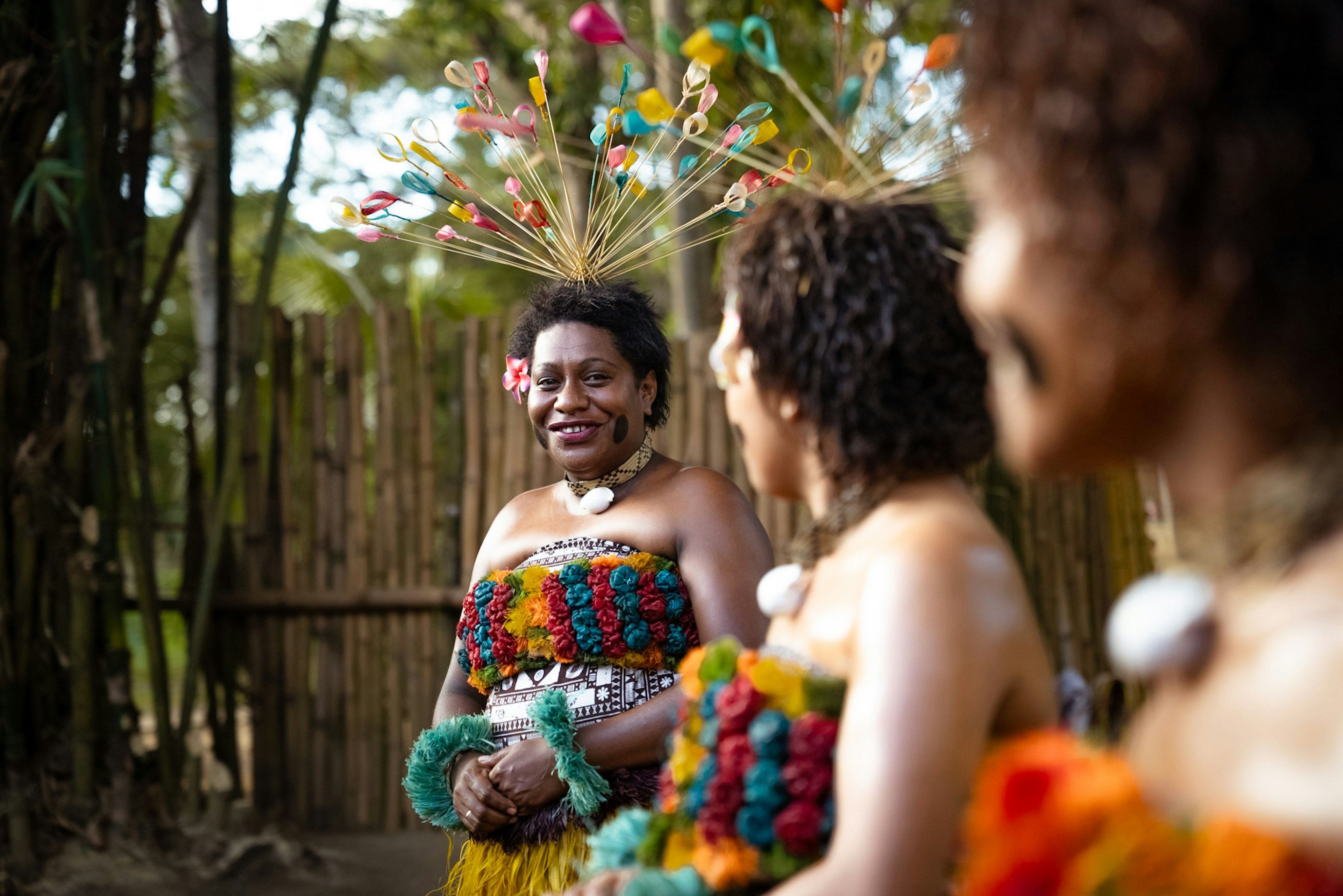 Two women in tradition festive dress smile at one another, Fiji