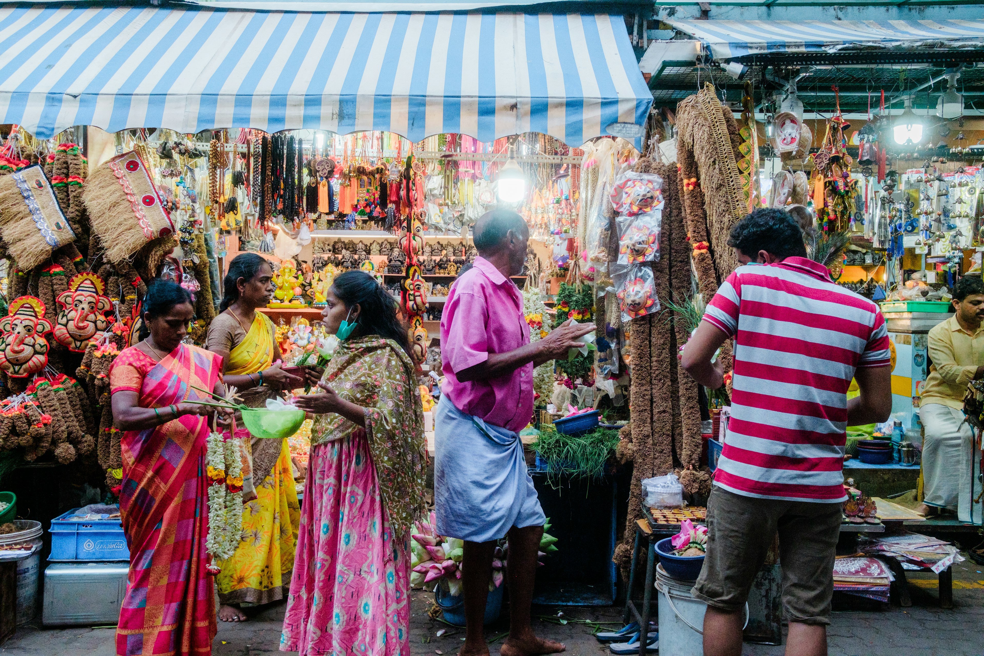 People in saris and brightly colored shirts transact business at market stalls in Puducherry (Pondicherry), India