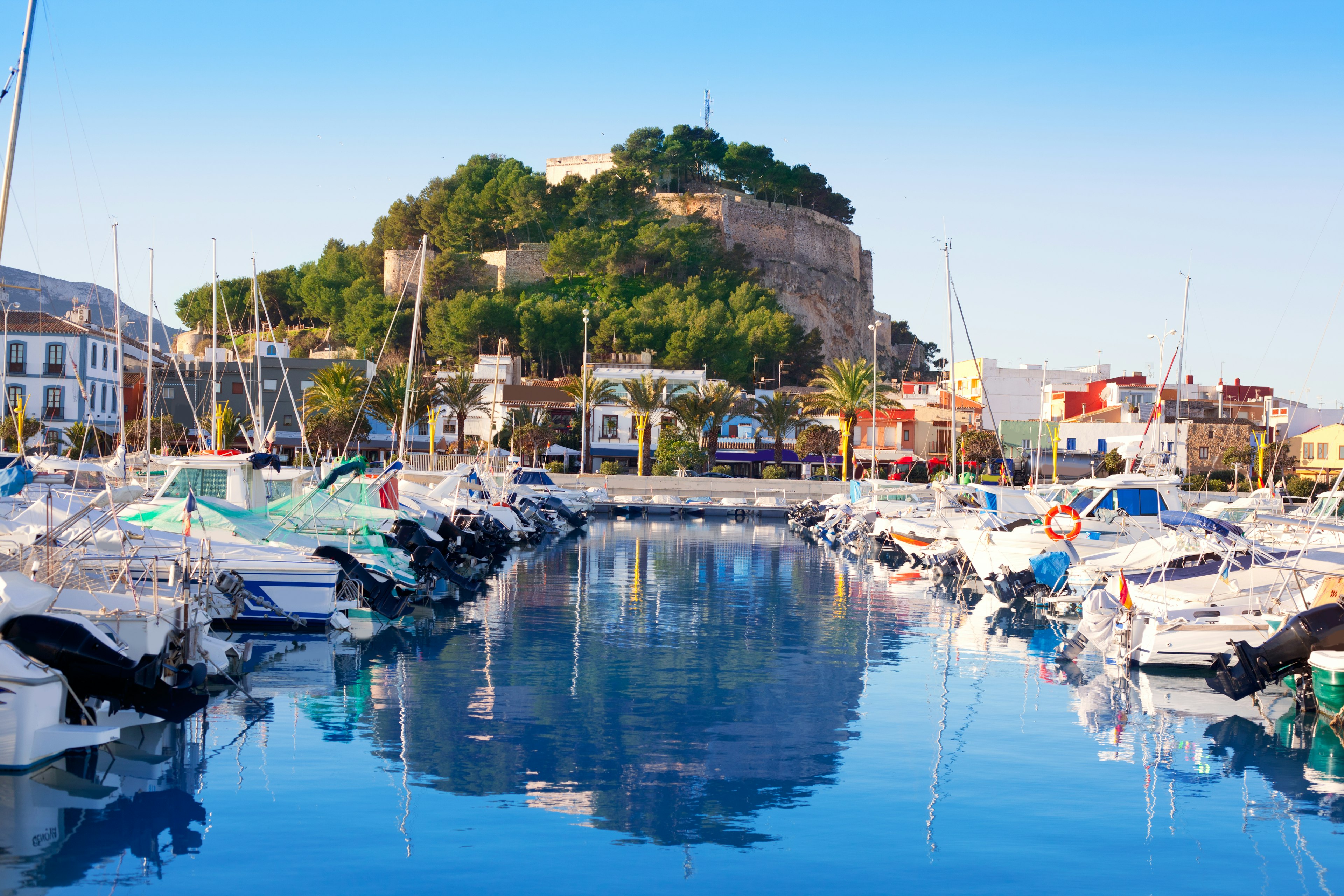 A small harbor packed with sail boats. A hilltop fortress overlooks the water