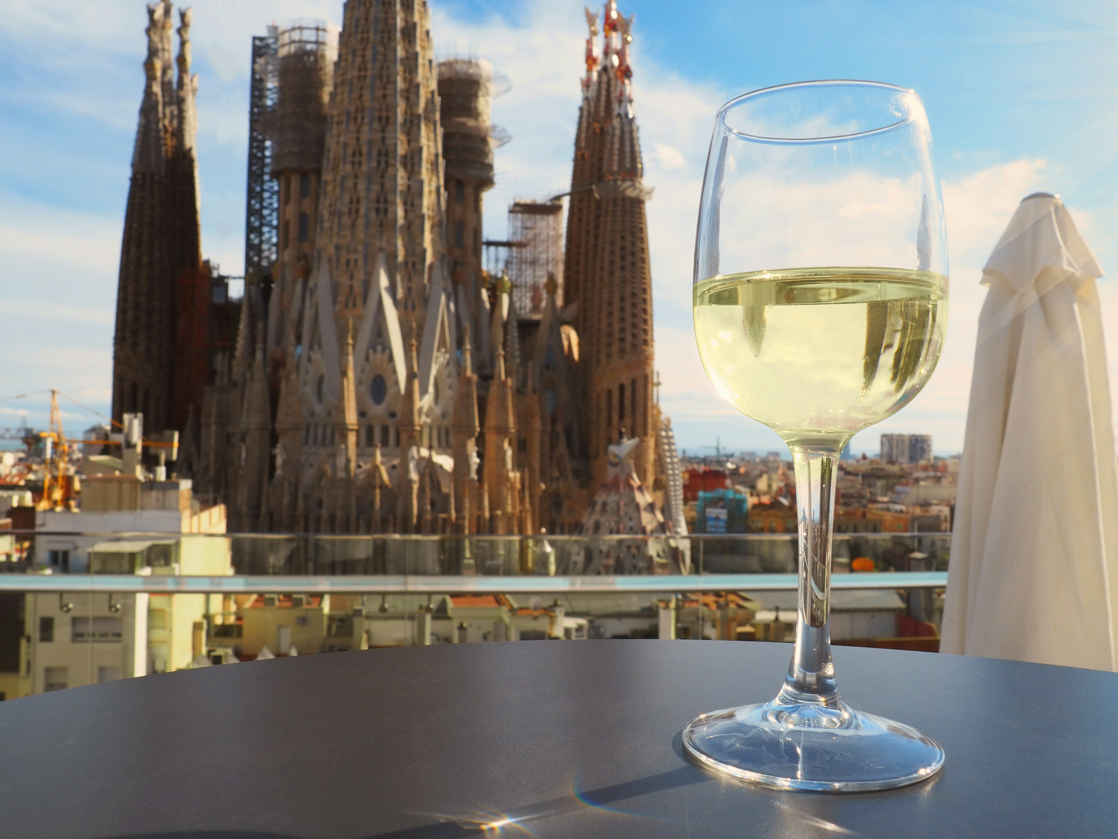 La Sagrada Familia, the cathedral designed by architect Gaudi, in the background with a class of white wine in the front.