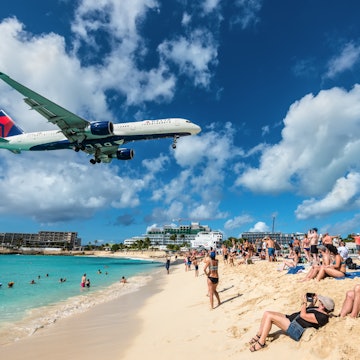 Maho beach, Saint Martin - December 17, 2018: The commercial jet Delta Air Lines approaches Princess Juliana airport above onlooking spectators in Maho beach, Sint Maarten - Saint Martin island., License Type: media, Download Time: 2024-10-03T17:54:19.000Z, User: jennifercarey0150, Editorial: true, purchase_order: 65050, job: Digital article, client: First time guide to St-Martin, other: Jennifer Carey