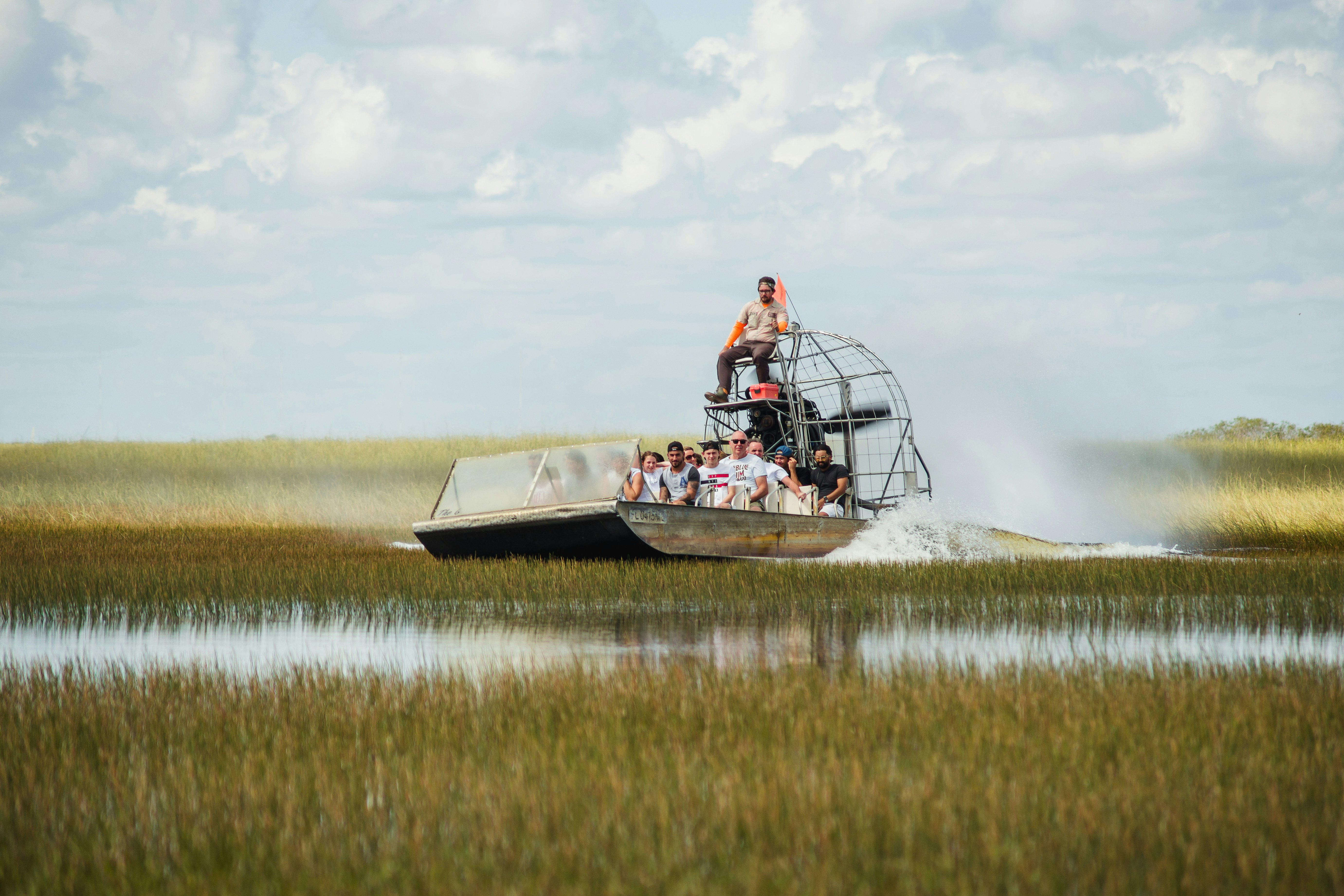 Tourists on an airboat speeding over flooded grassland in Everglades National Park, Florida, USA.