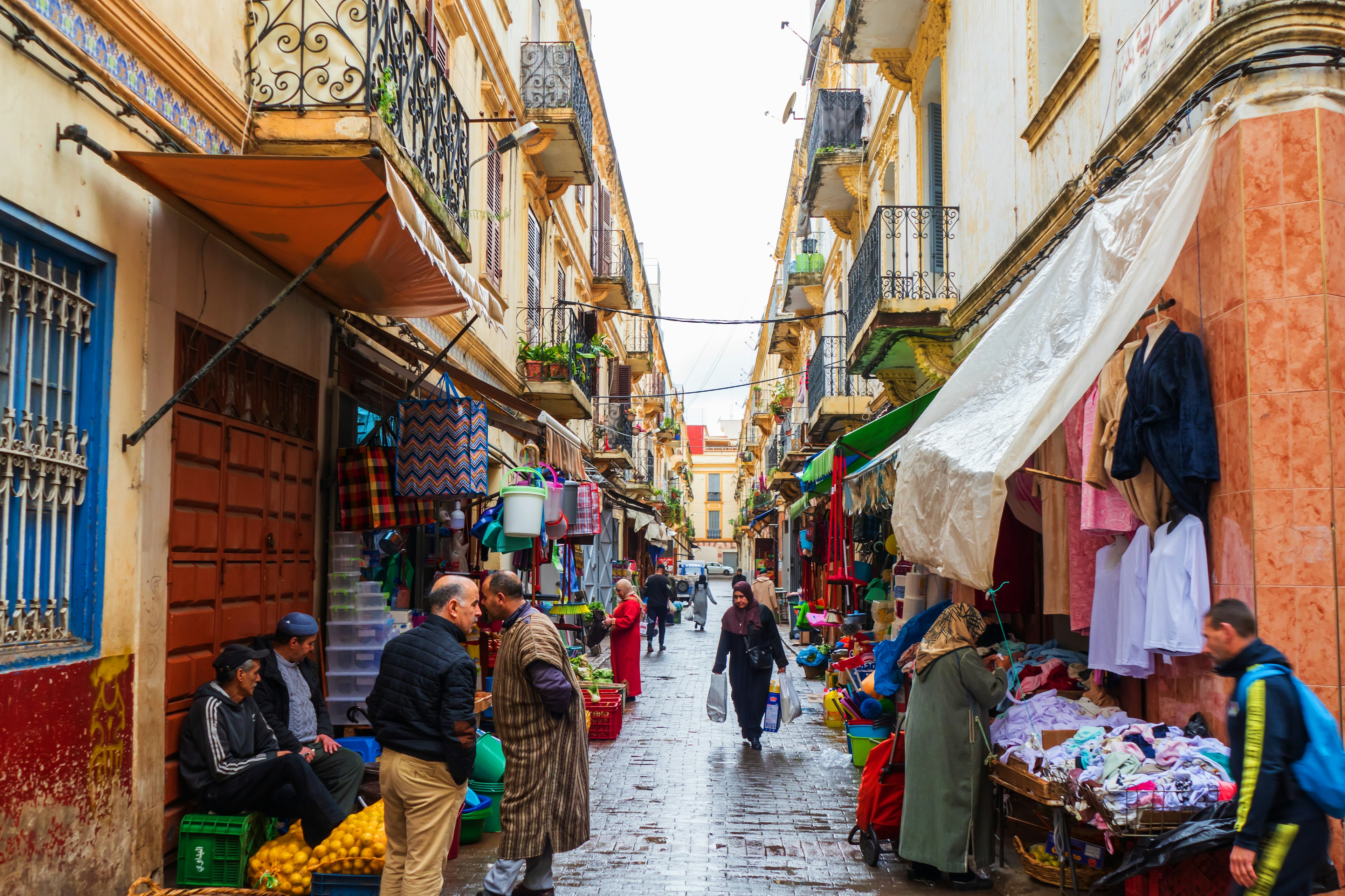 A shot looking down an alley in Tangier; the light is warm and there are many people milling about outside shops.