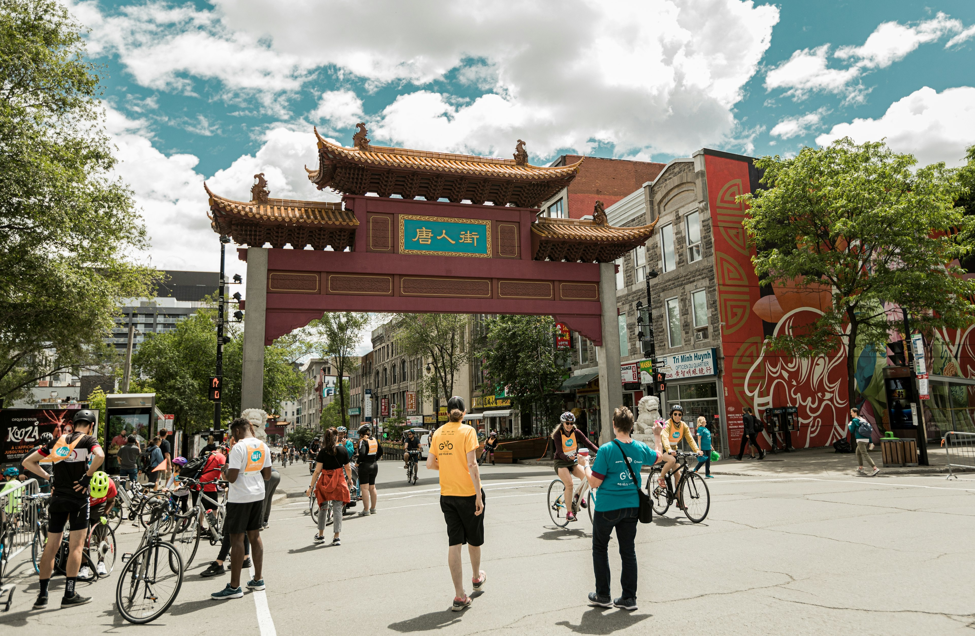 People with bicycles stand near the Gate of China Town (South Paifang) on Blvd St-Laurent in ѴǲԳٰé, Québec, Canada