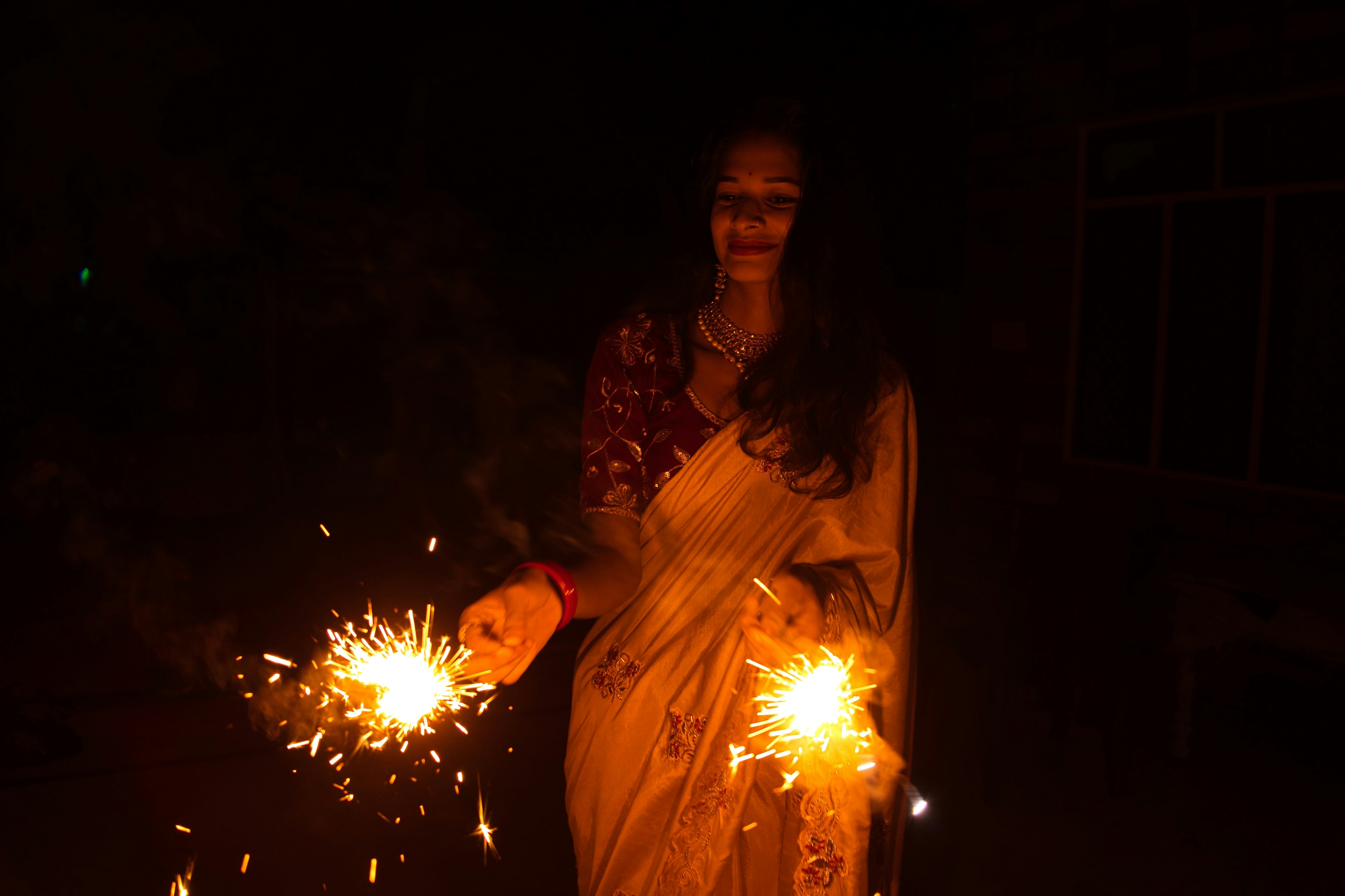 A girl holding sparklers with diya lamp during diwali celebration.