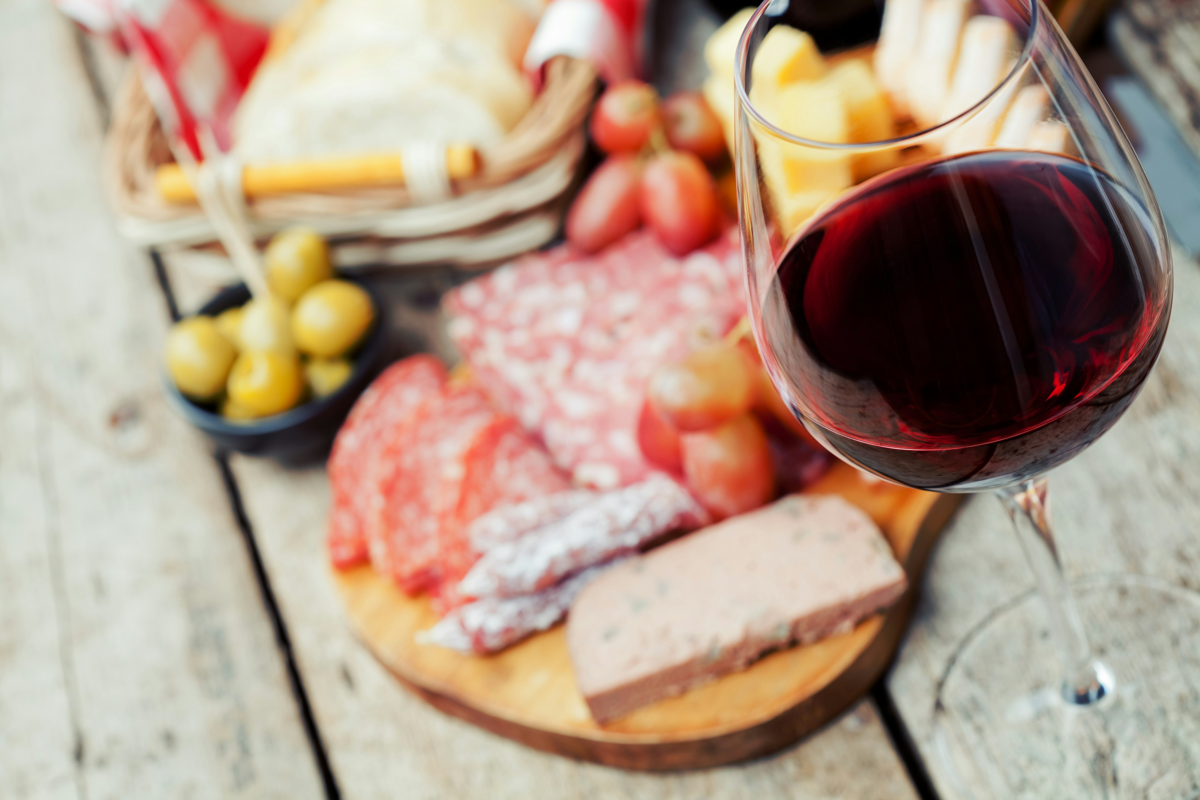 Glass of red wine with charcuterie assortment on the background.