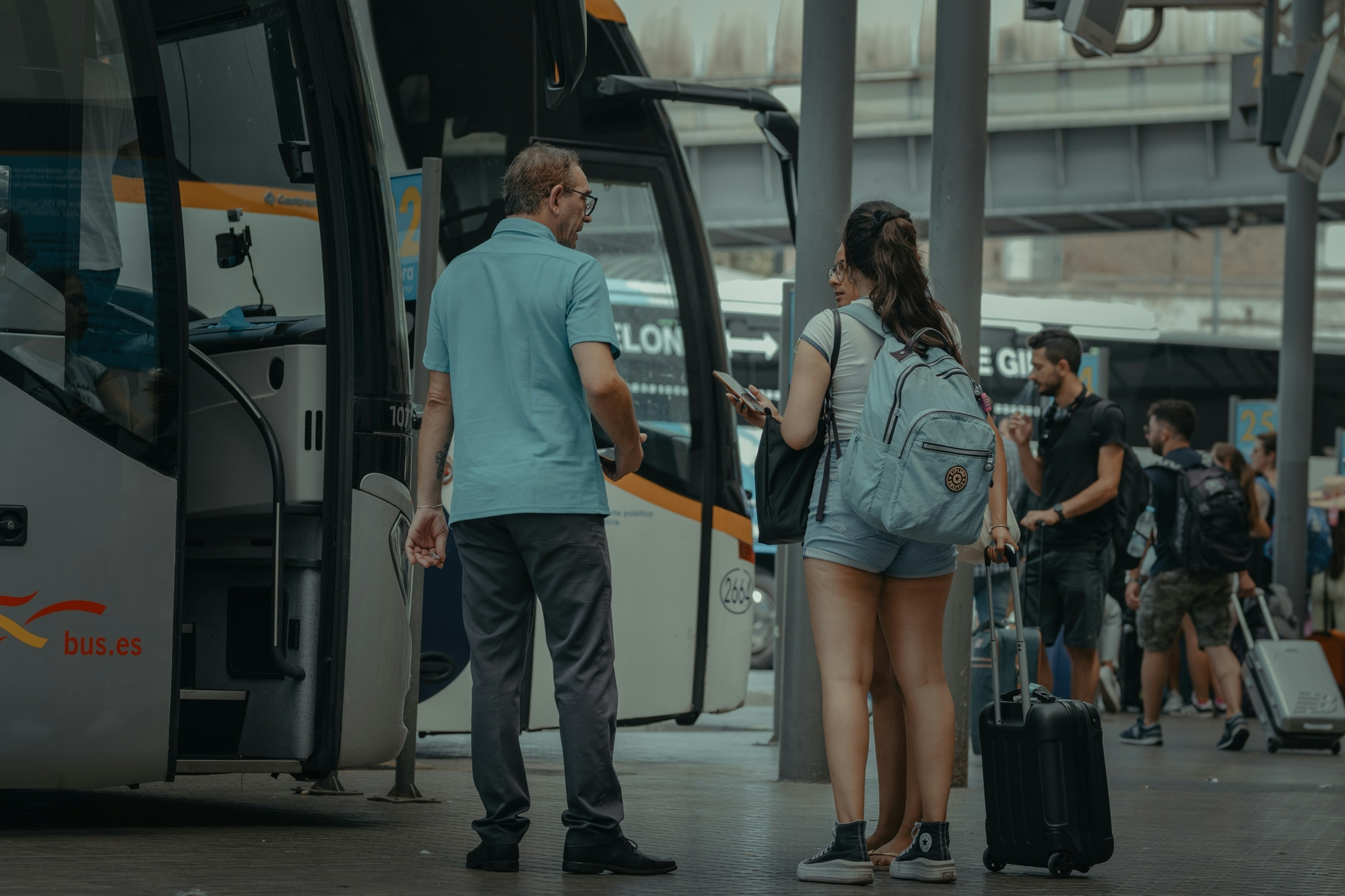 View of a bus driver giving information to two passengers at the bus station.