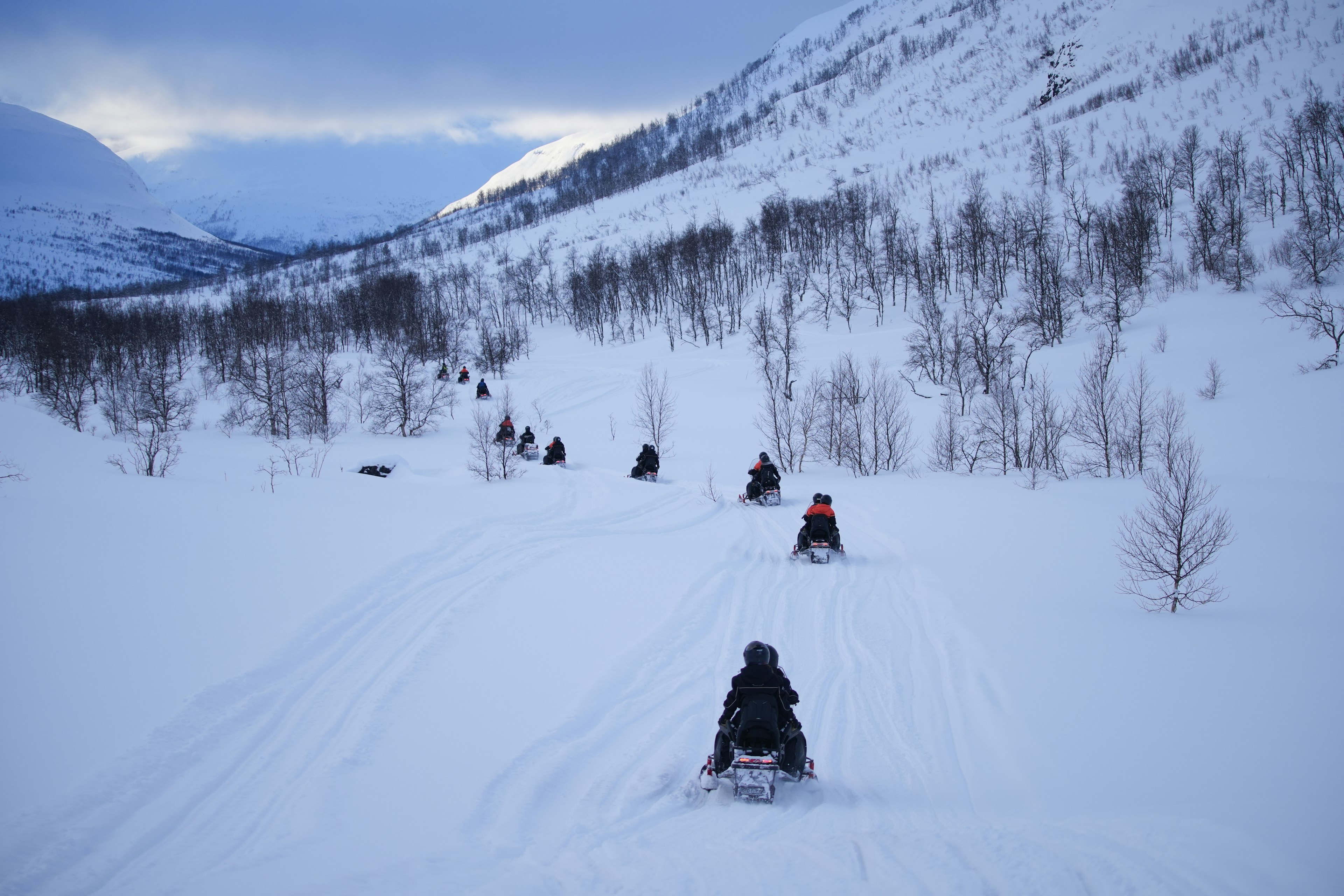 A group of people riding snowmobiles through crisp snow