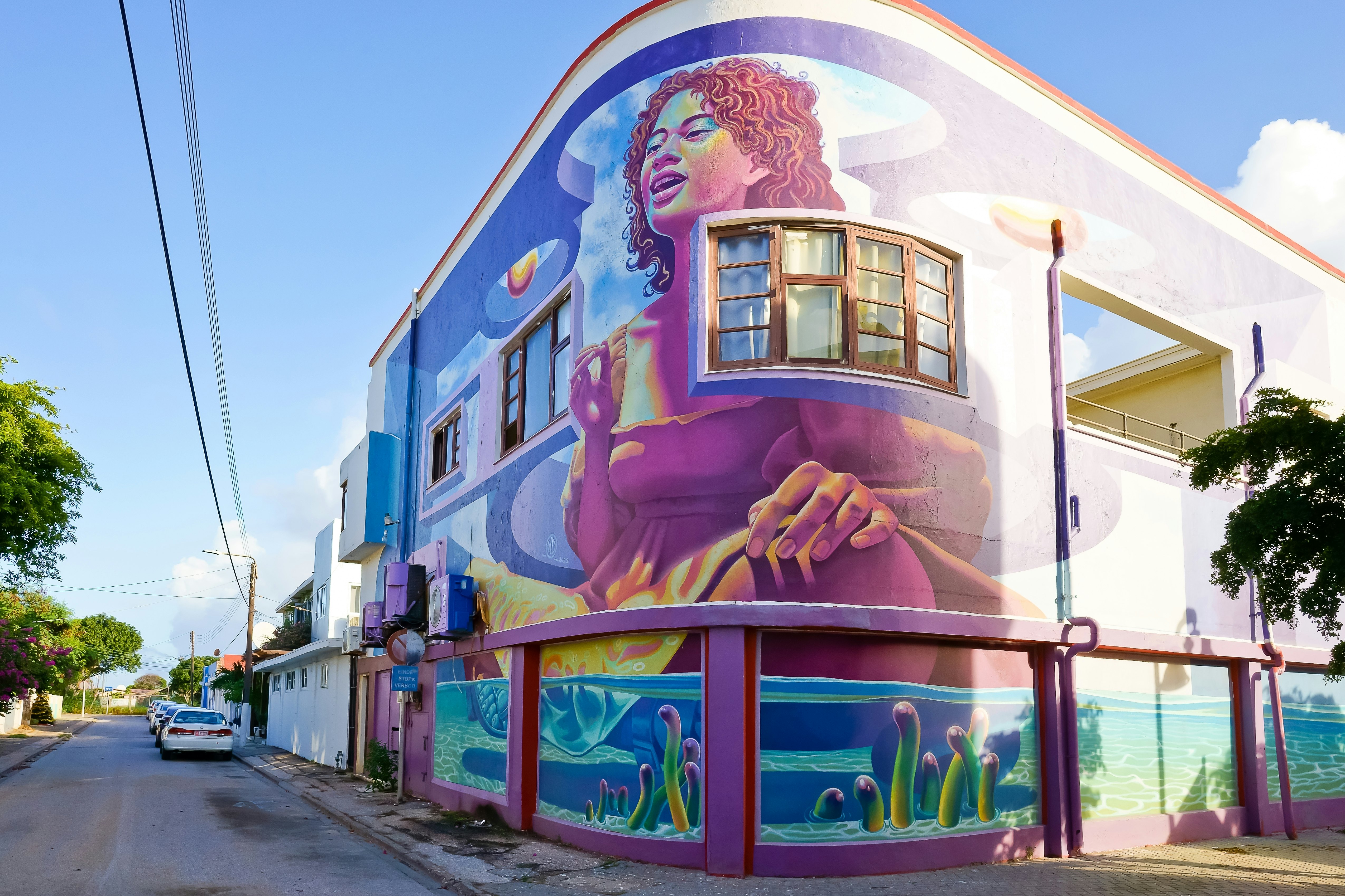 The painted mural, “Hymn to the Sea” by Wild Drawings on the curved facade of a building in San Nicolas, Aruba