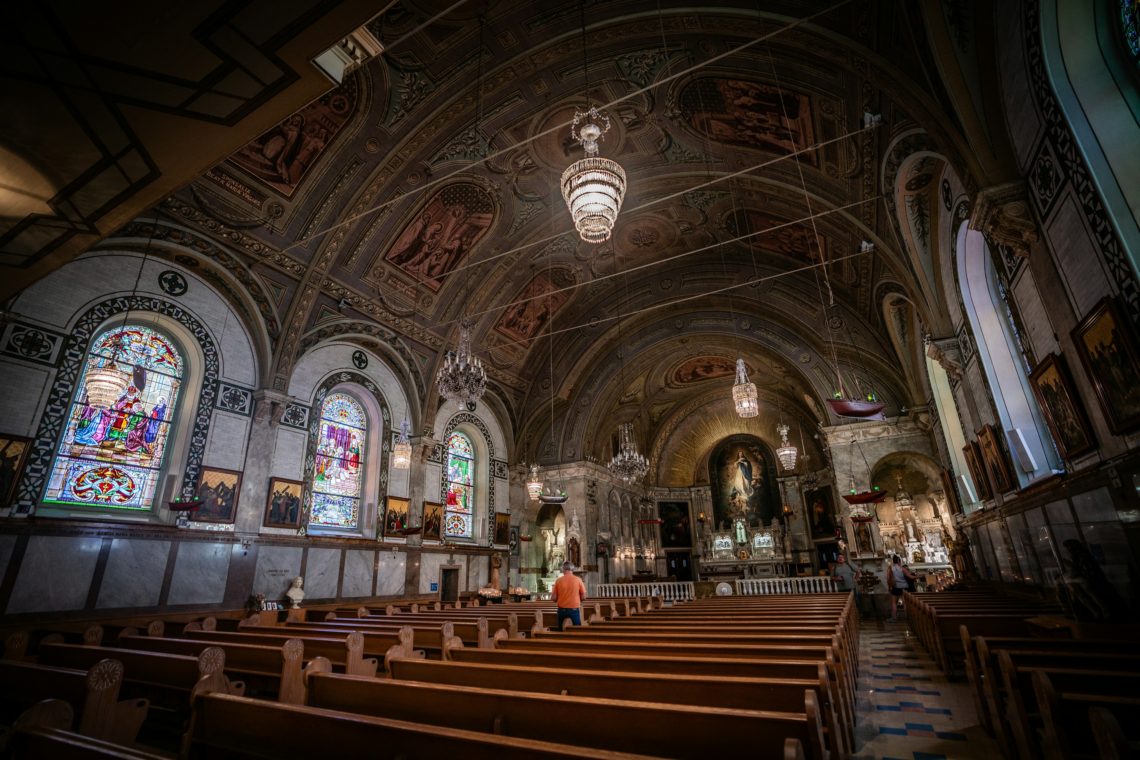 A person prays in the nave of Notre-Dame-de-Bon-Secours Chapel, filled with ceiling frescoes and stained-glass windows, Montréal, Québec, Canada