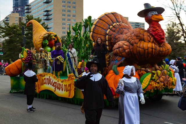 Pilgrims march alongside a turkey float in the annual Thanksgiving Day parade in Chicago