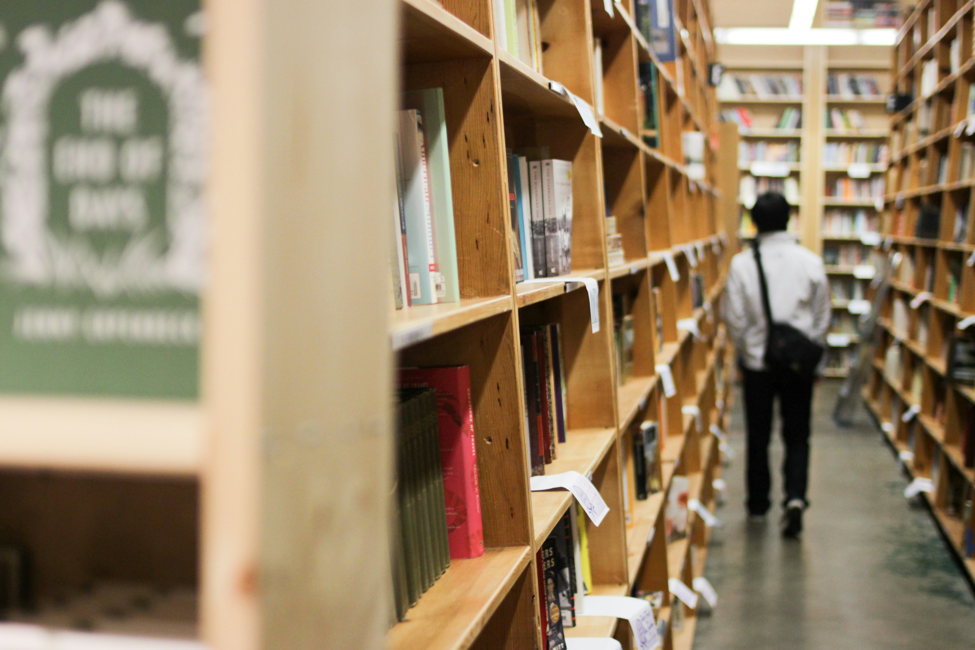 A man walks down an aisle of bookshelves brimming with titles for sale at Powell’s World of Books in Portland, Oregon, USA