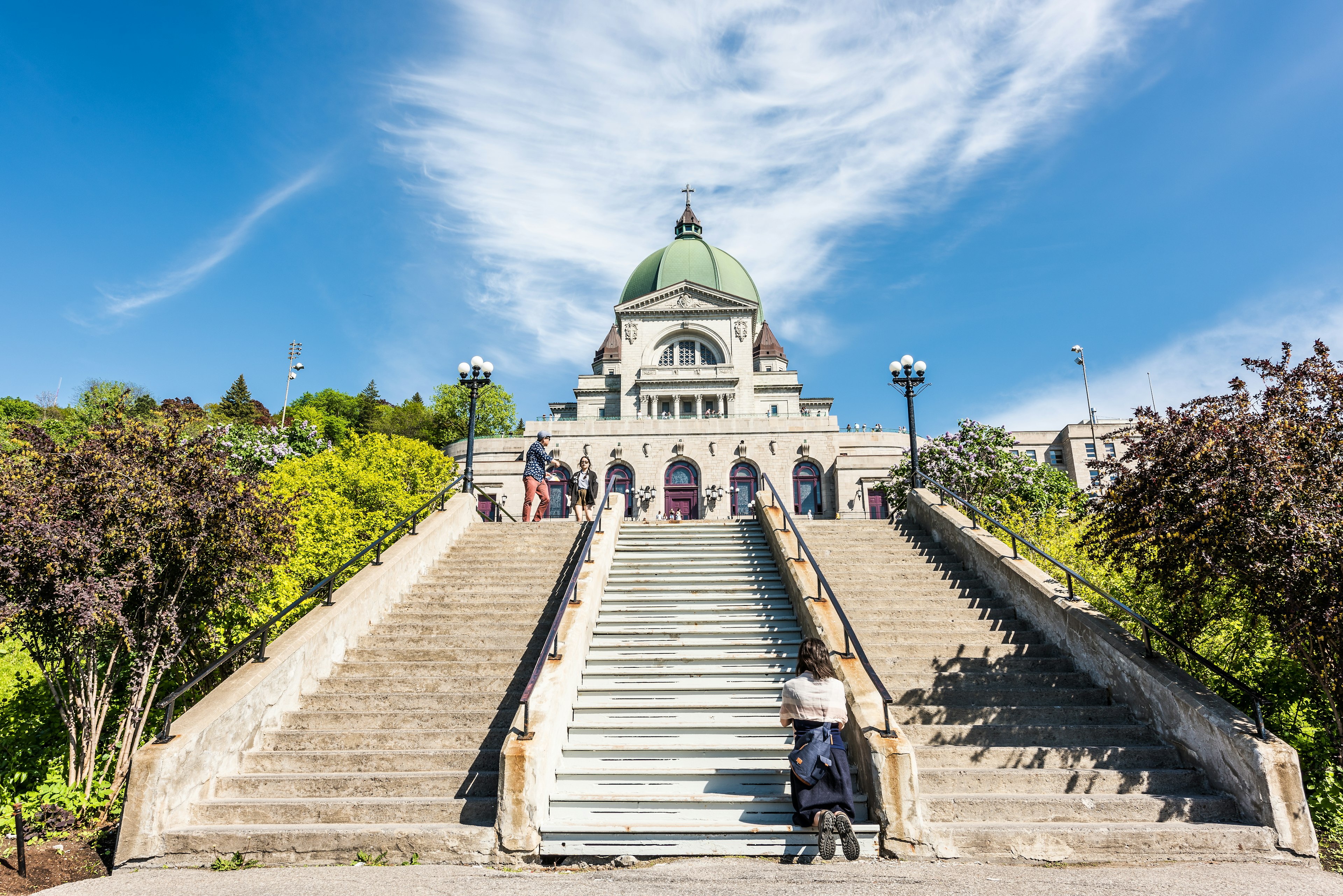 A woman kneels in prayer on the steps leading up to Oratoire St-Joseph, Montréal, Québec Canada