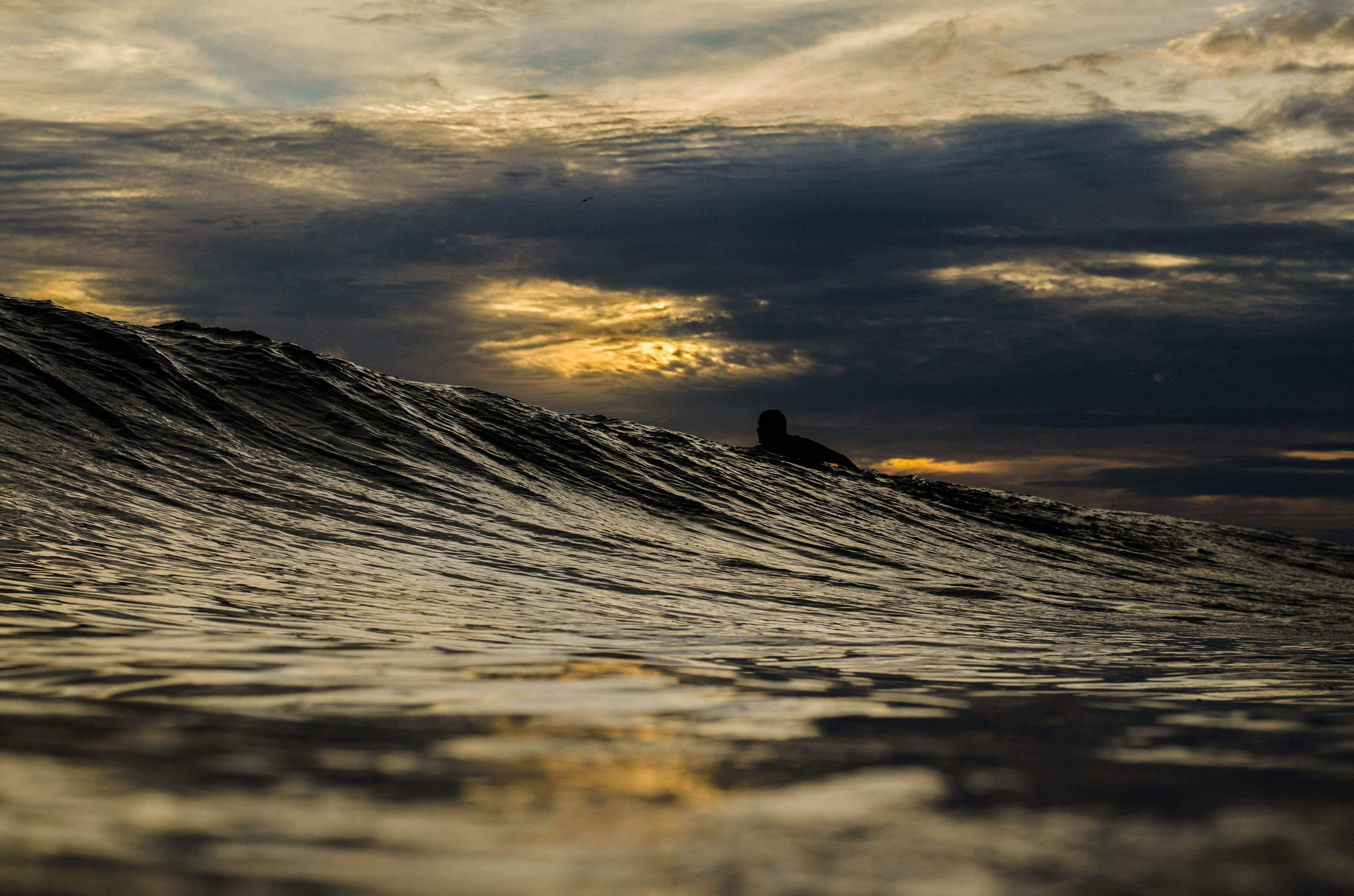 A silhouette of a surfer paddles over a breaking wave in Nicaragua.