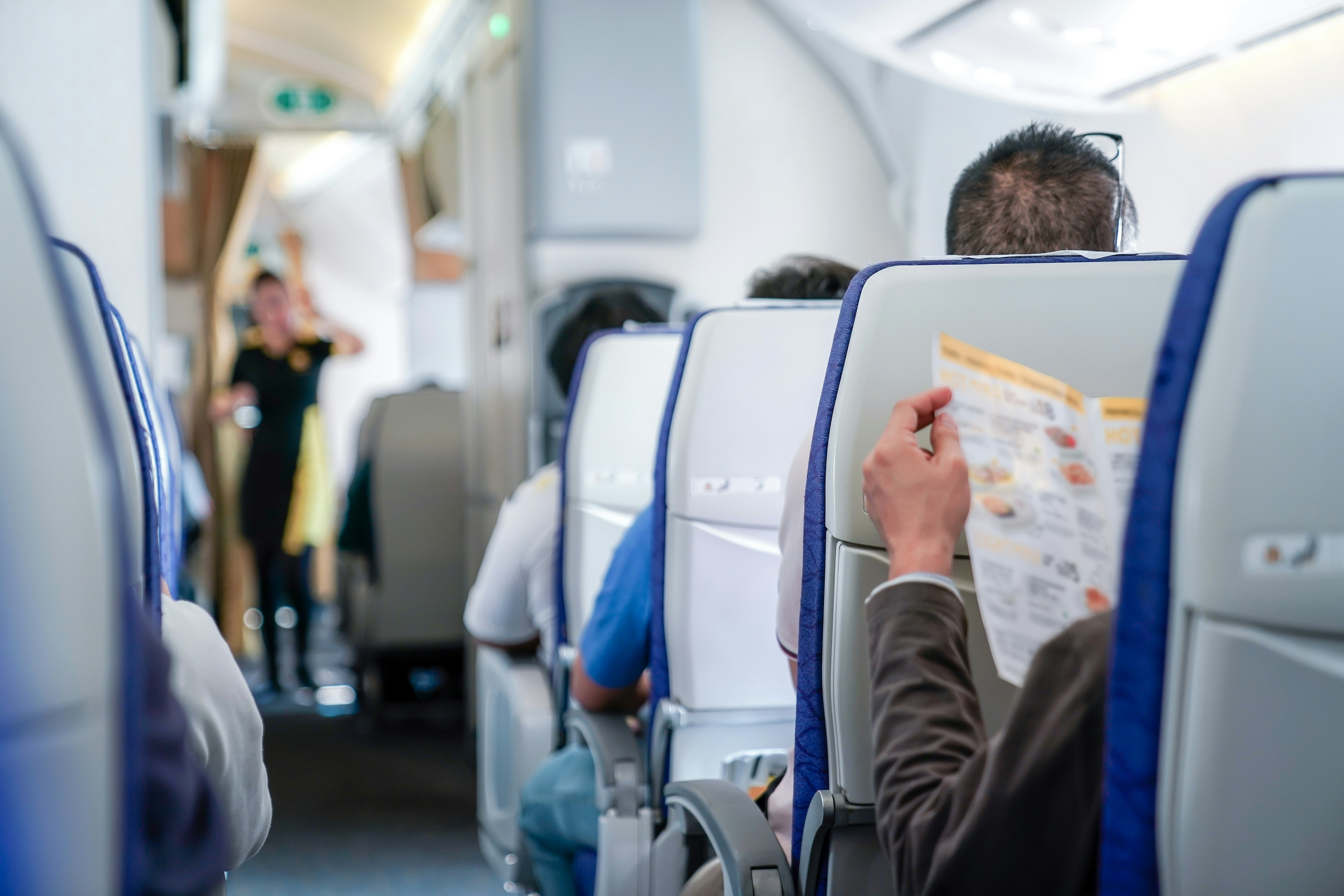 The view from an aisle seat on a plane. A steward is visible but out of focus