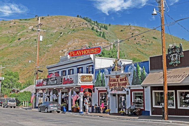 People outside an old playhouse in a town with Wild-West vibes dressed in shorts and T-shirts on a sunny day