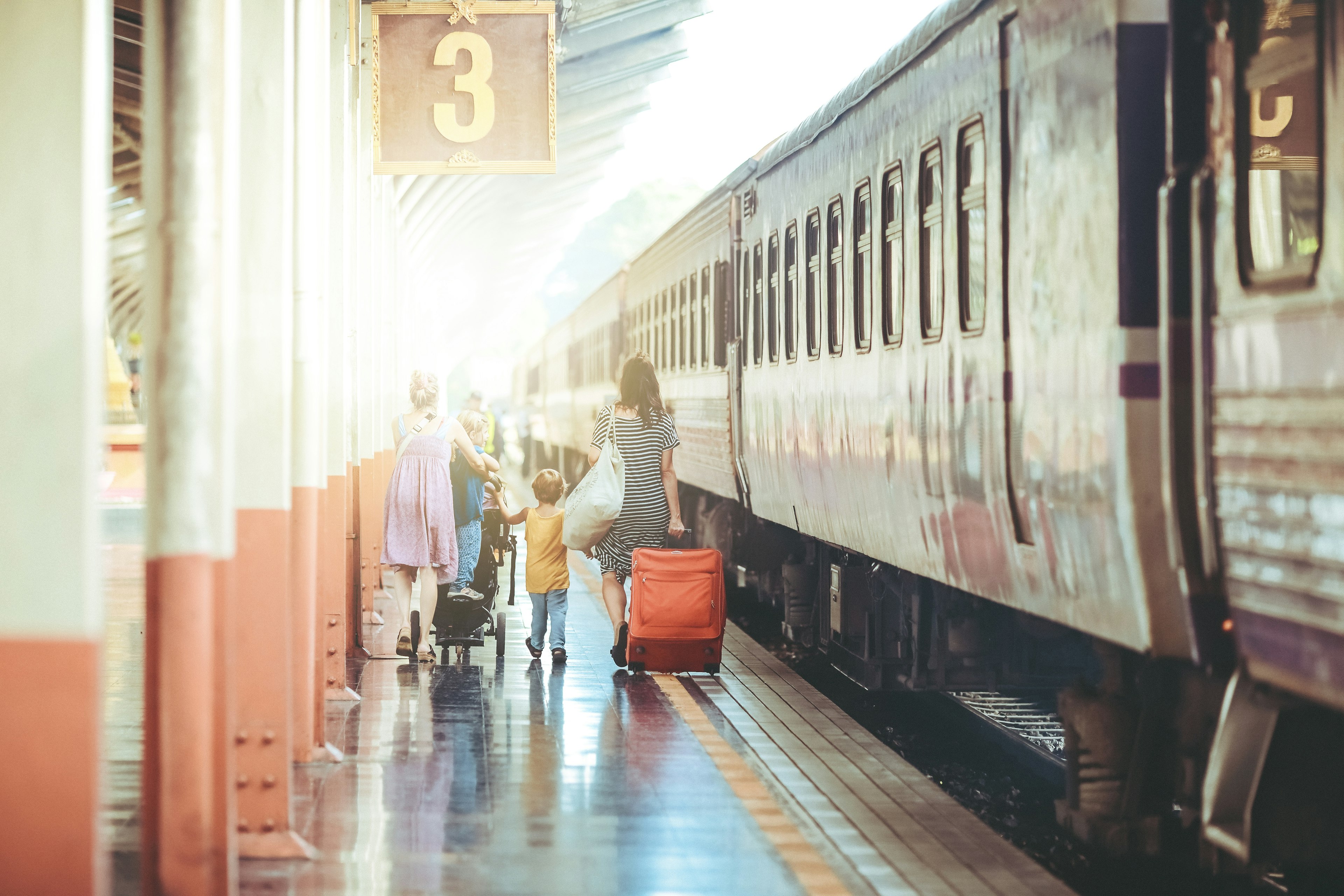 Travellers walking alongside a train on platform three of a station..