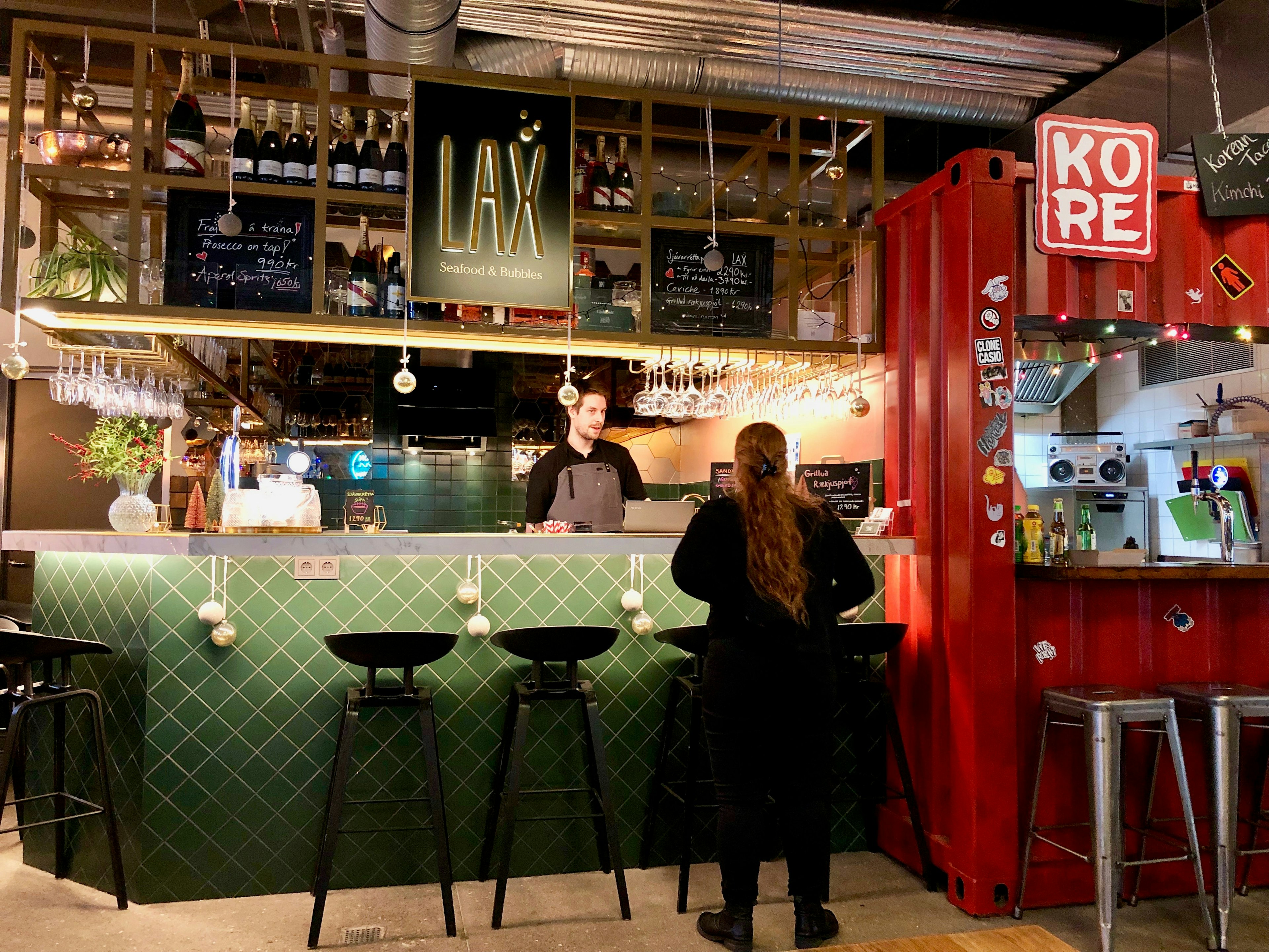 A customer chats to a server in an indoor street food market