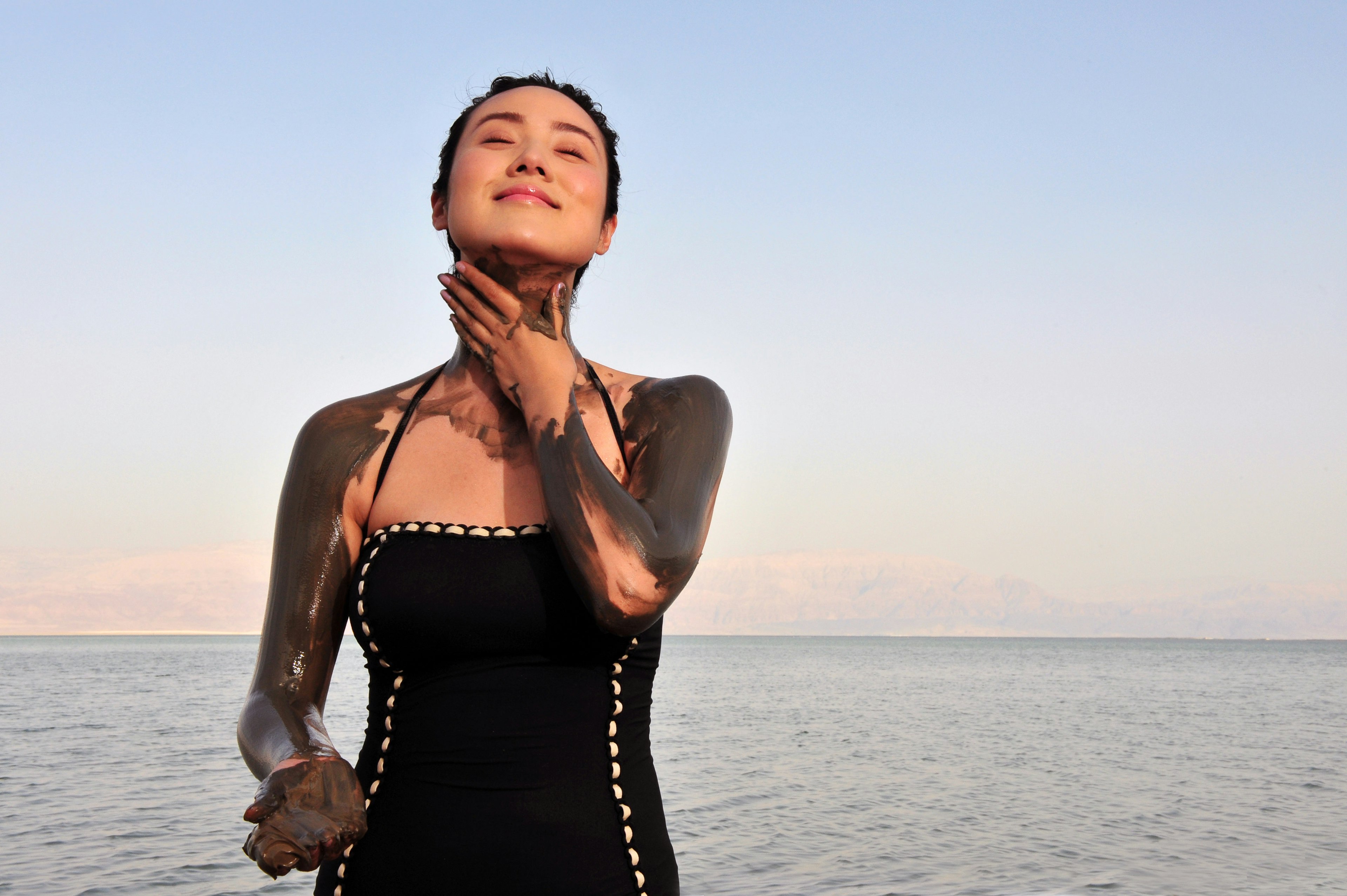 A woman covers herself in black mud from the Dead Sea.