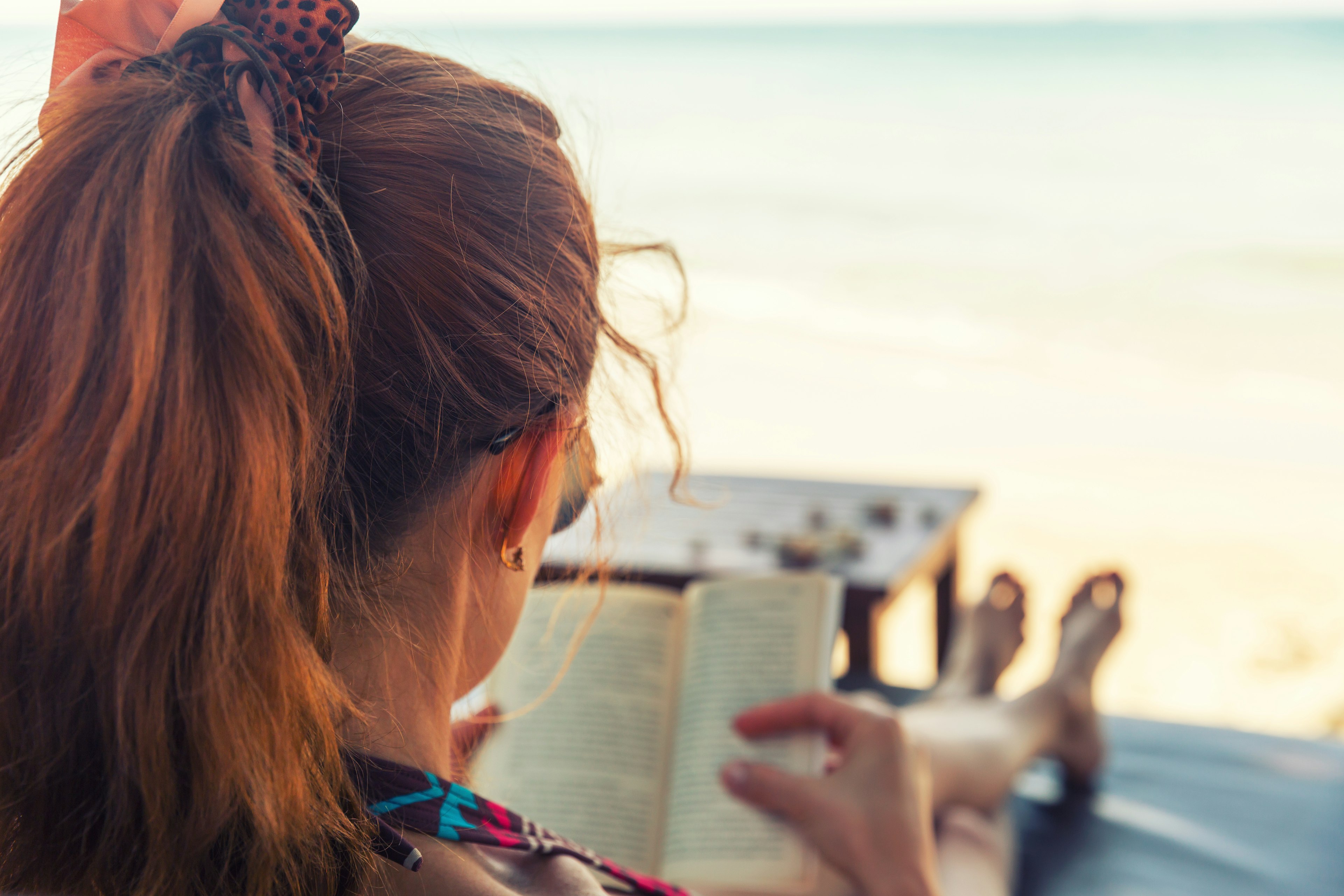 Young woman reading a book at a beach.