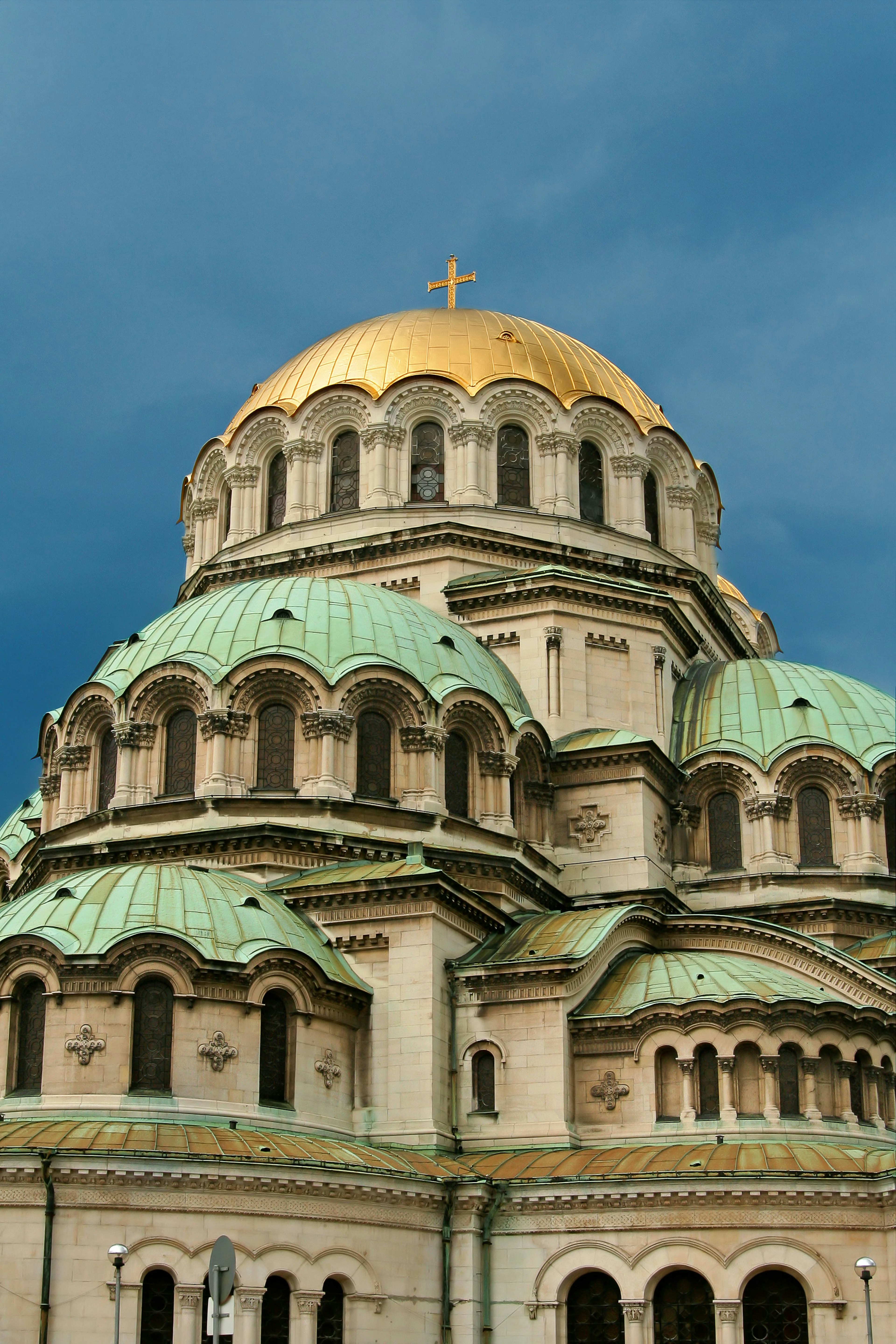 A large white church with several domed roofs in gold and teal colours