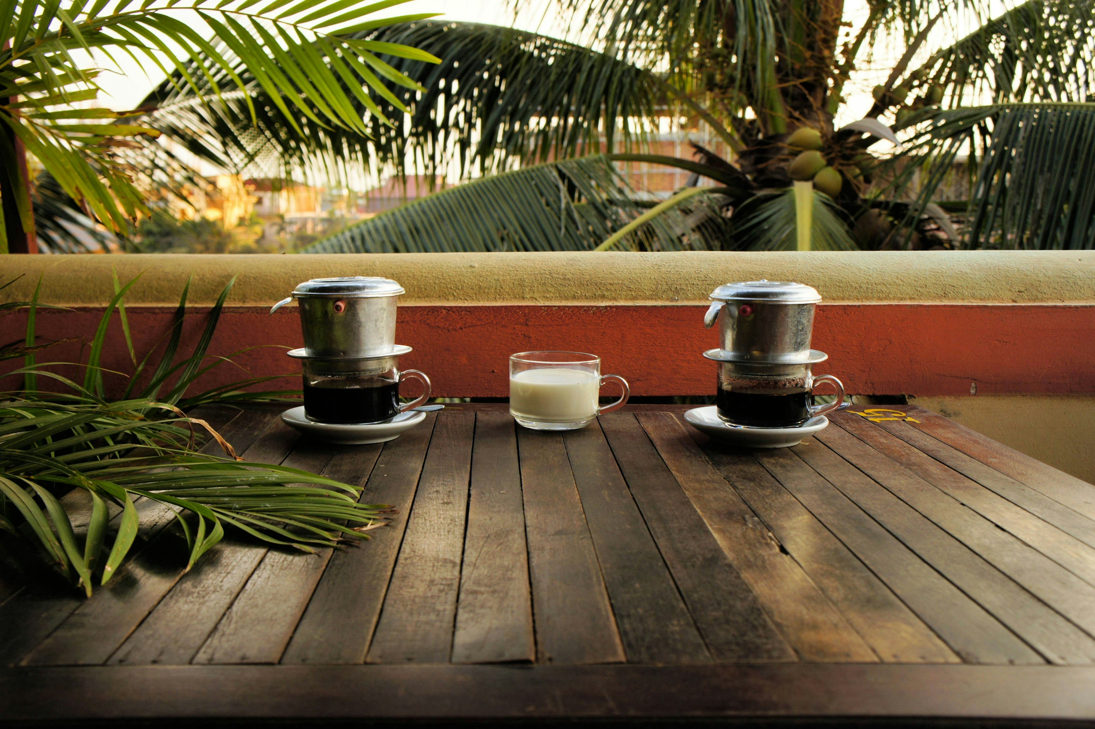 Coffee dripping in Vietnamese style with milk Ca Phe Sua under palm trees.