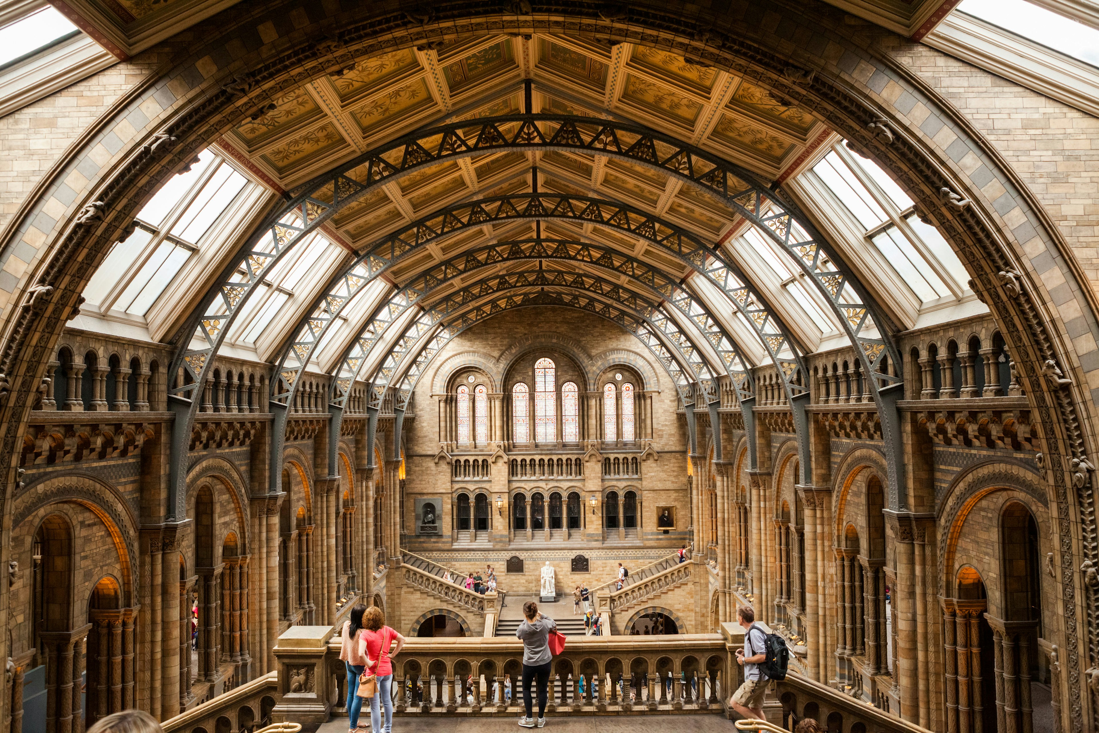 The interior of the Natural History Museum, a few visitors fill the staircase in the middle of the photograph.