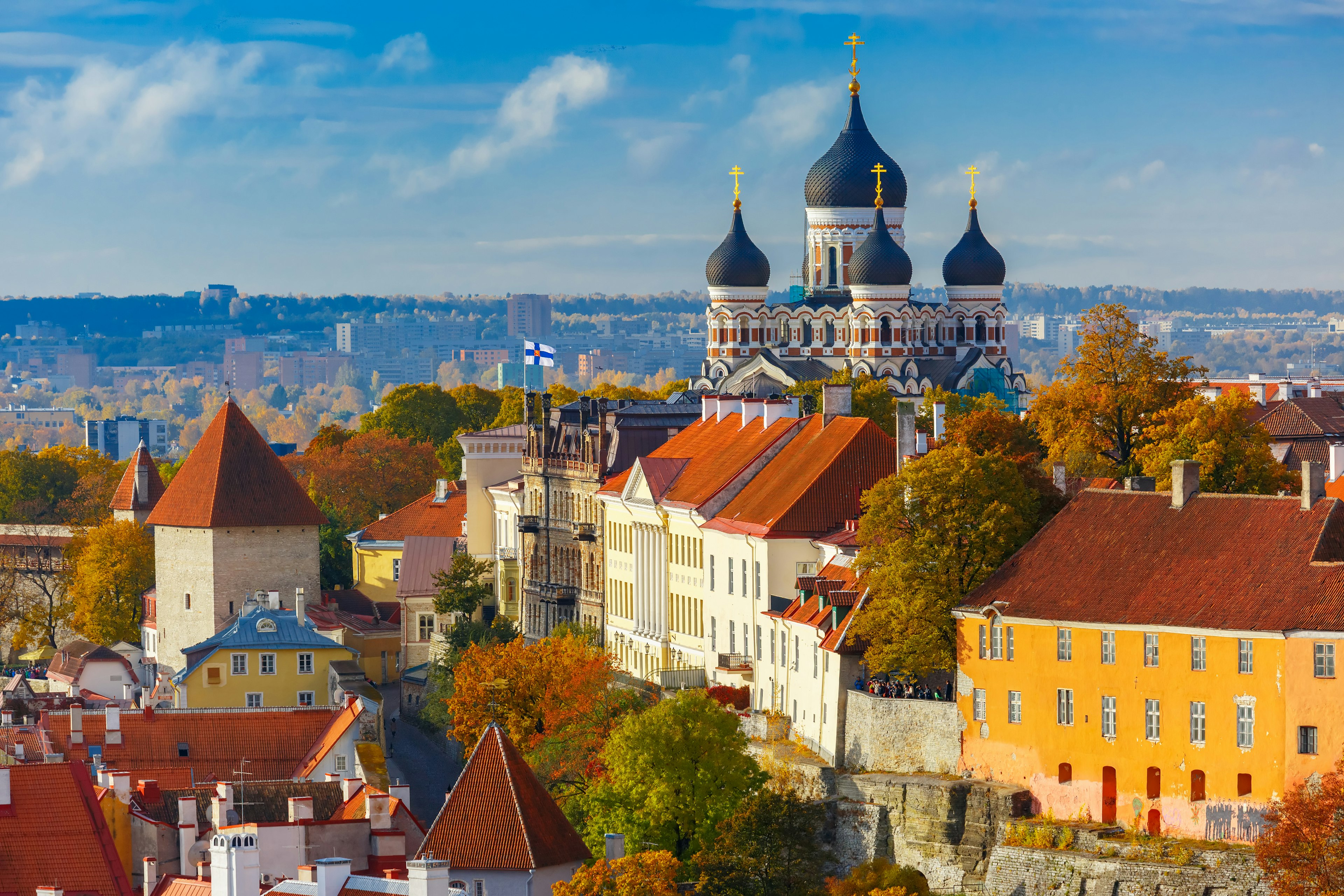 A view dominated by four huge domes of a cathedral, each topped with gold crosses. Large red-roofed buildings are in the foreground