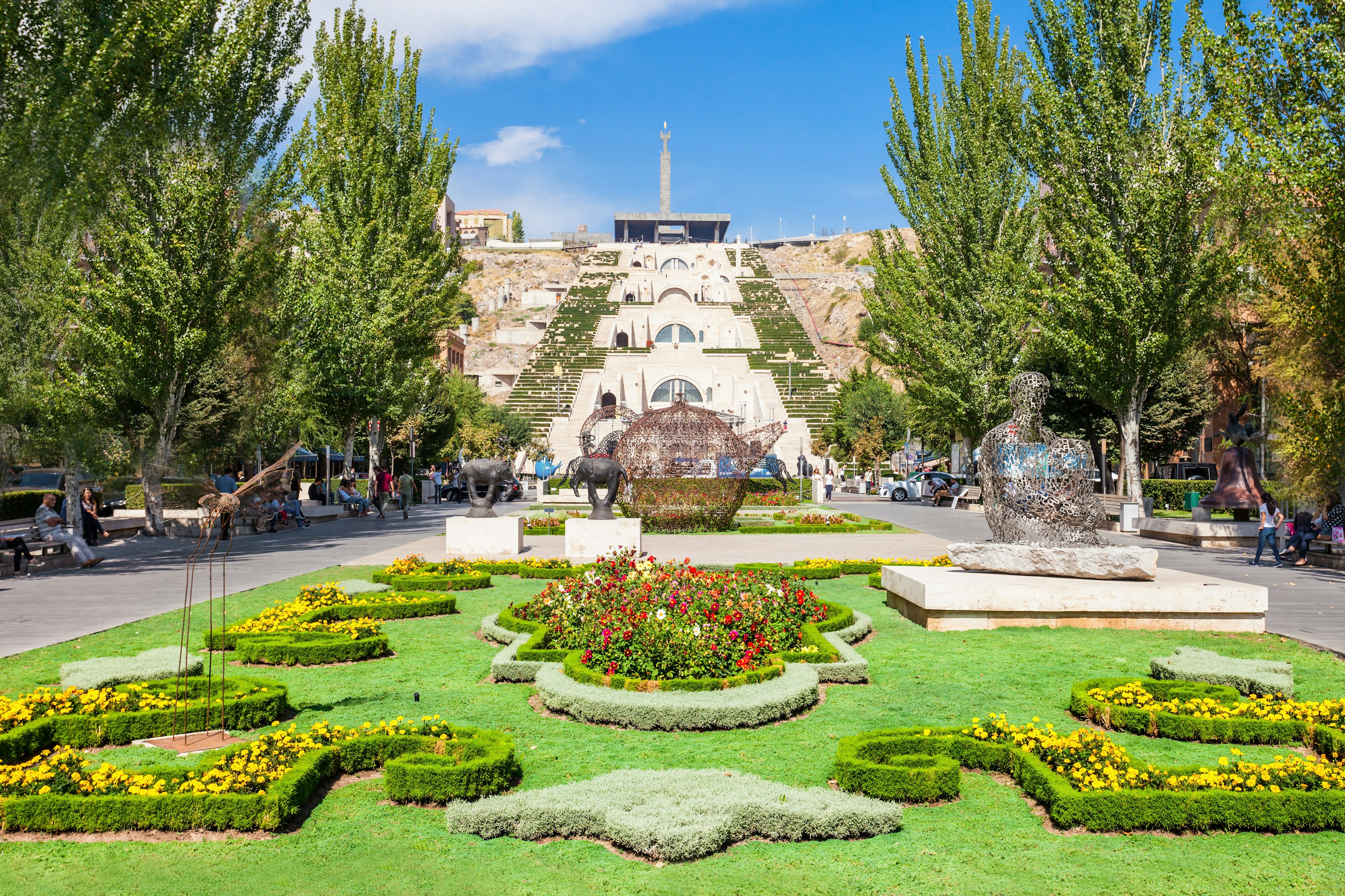 A sprawling garden with decorative bushes and trees in front of The Cascade in Yerevan, Armenia.