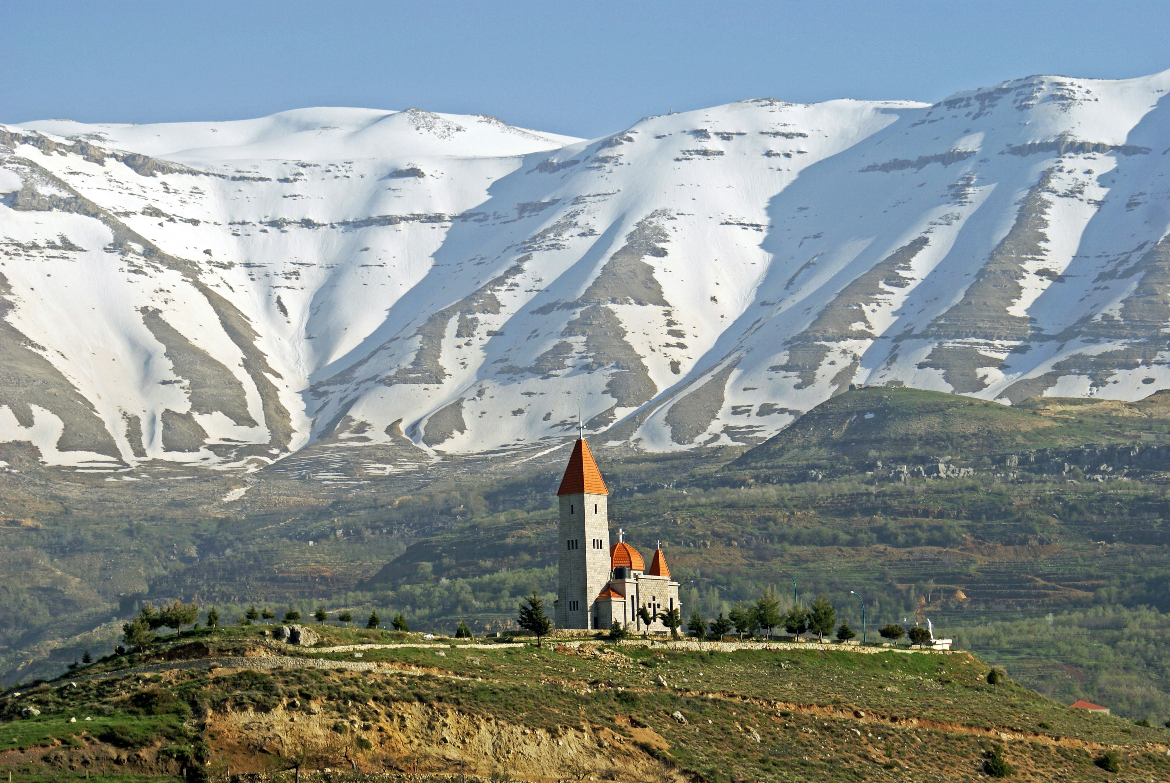 Sacred Heart Church in Bcharre, with snow-covered mountains beyond.