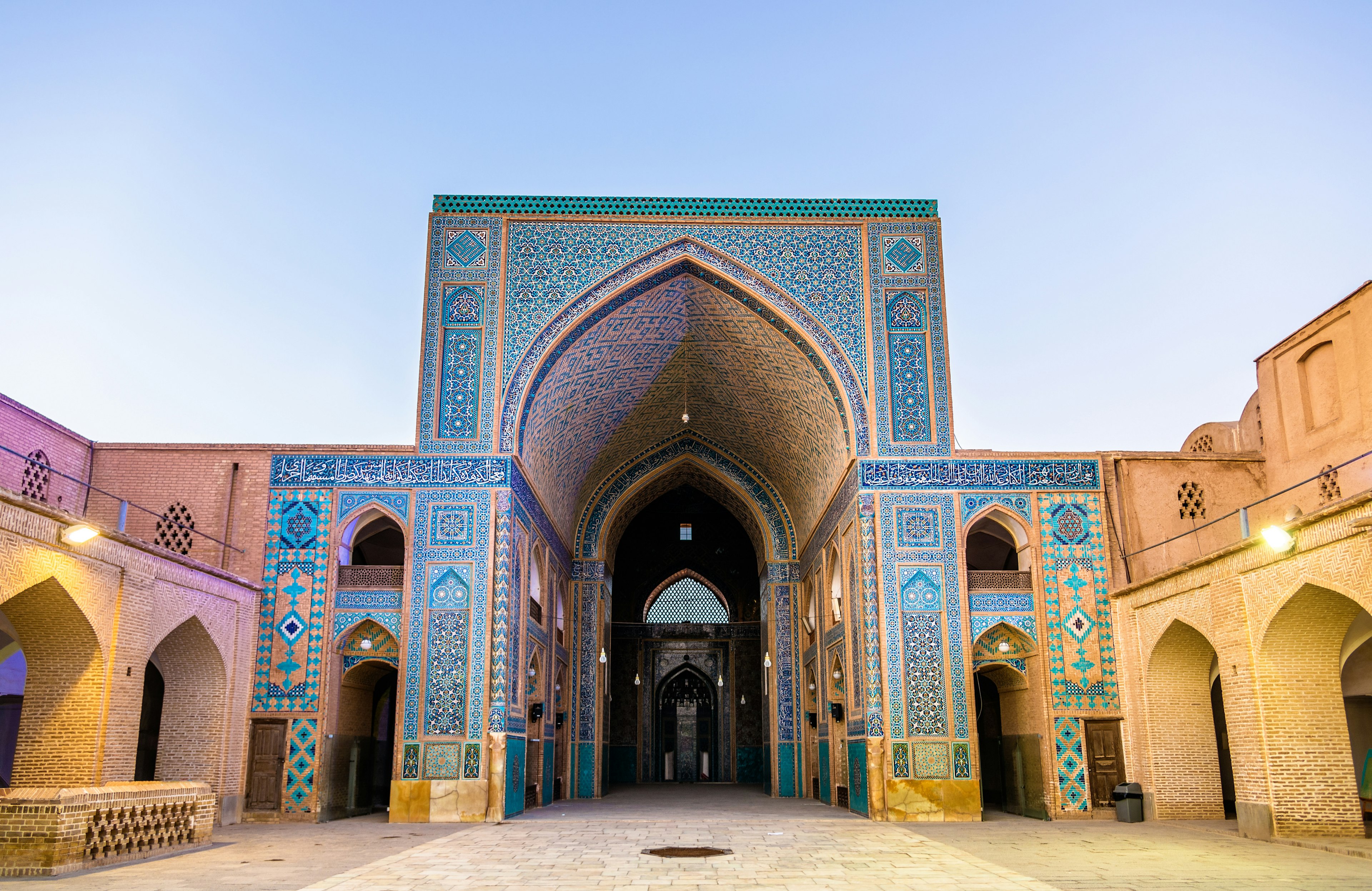 The courtyard of the Jameh Mosque of Yazd in Iran. The building is covered in intricate tile patters, predominantly shades of blue with some yellow