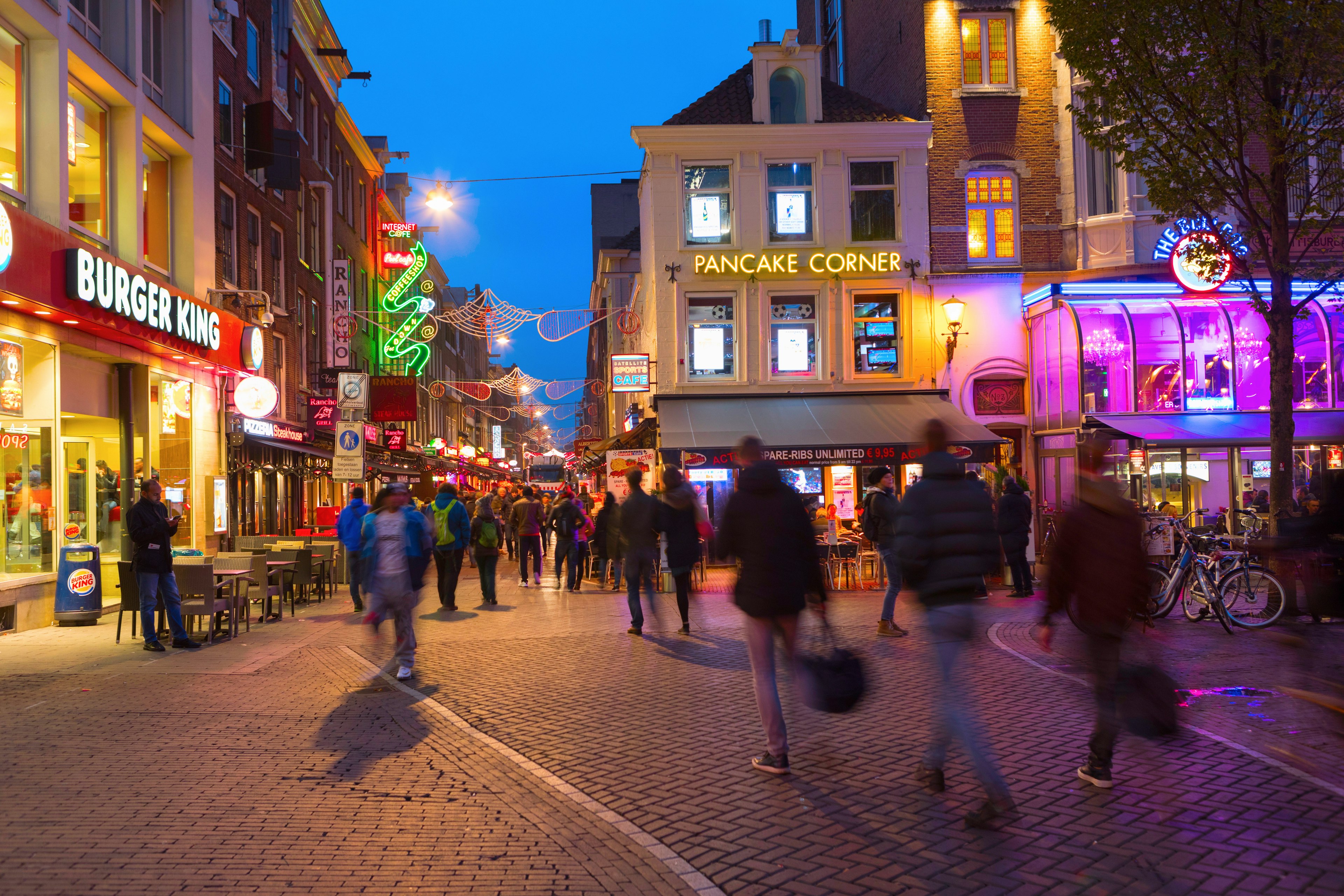 Long exposure of pedestrians in the Leidseplein/Leidsebuurt area at night.