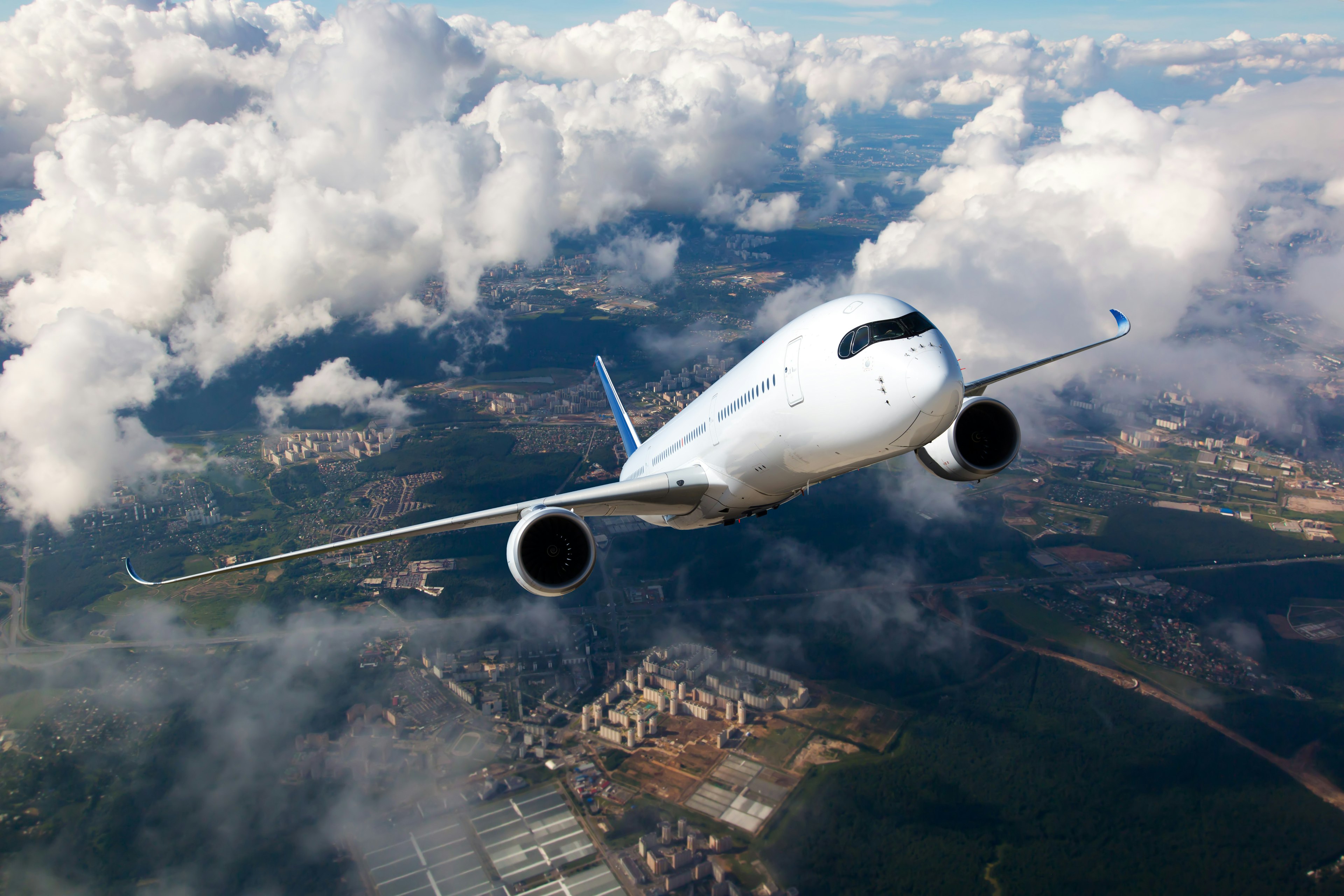 White passenger plane climbs through the clouds above a city.