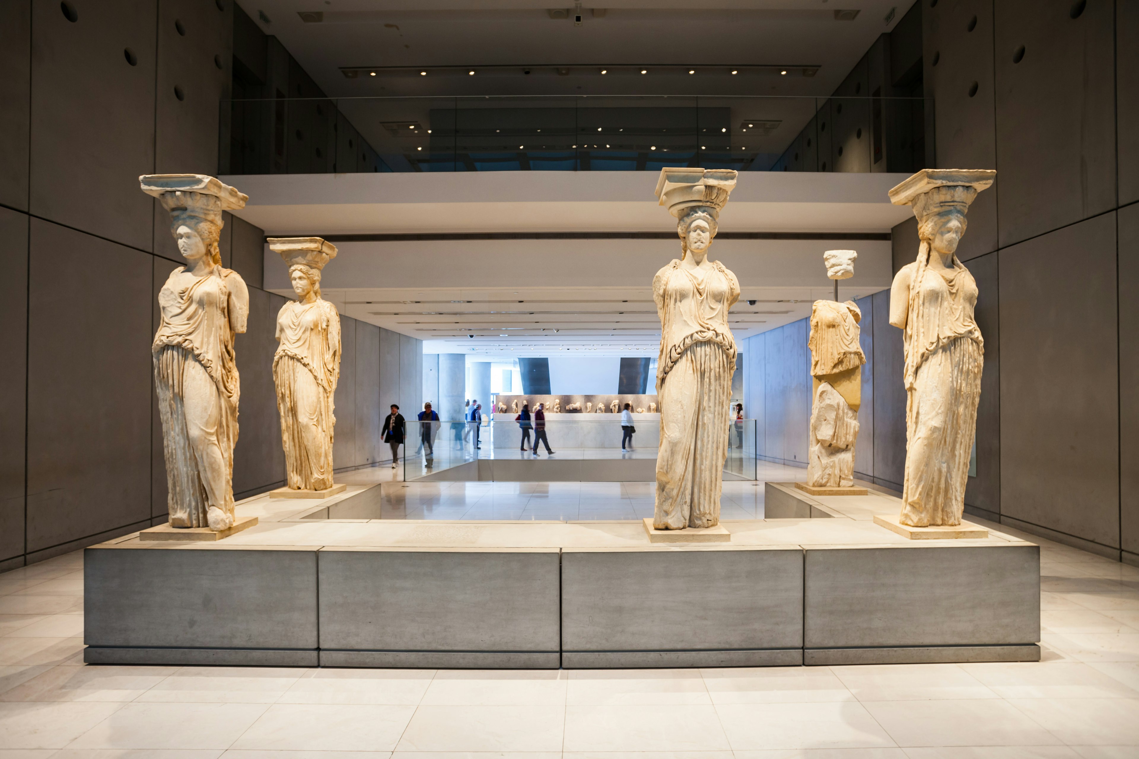 Five armless (and one headless) marble statues stand on a u-shaped plinth.