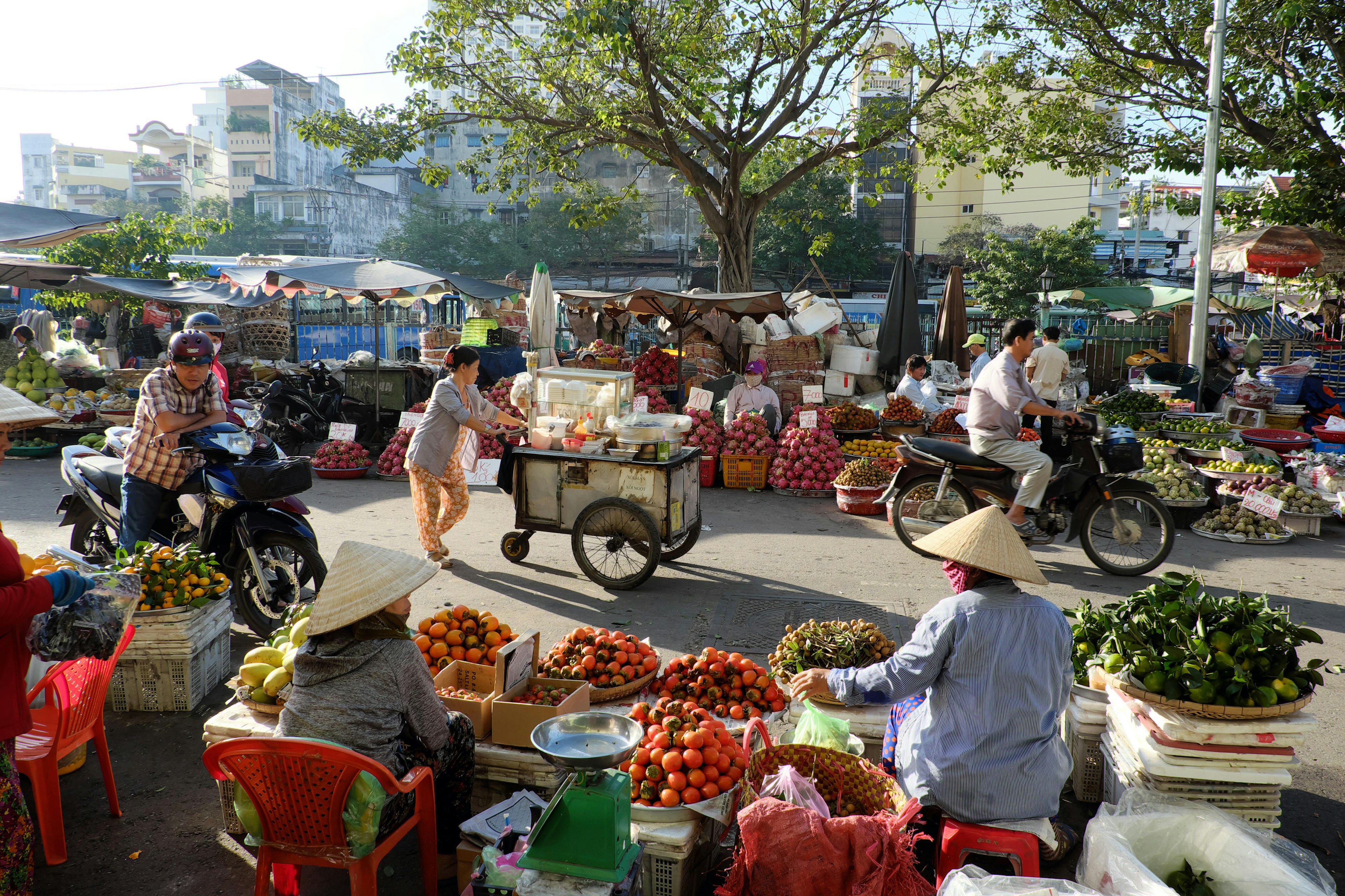 Market vendors selling fresh fruit and veg line a street