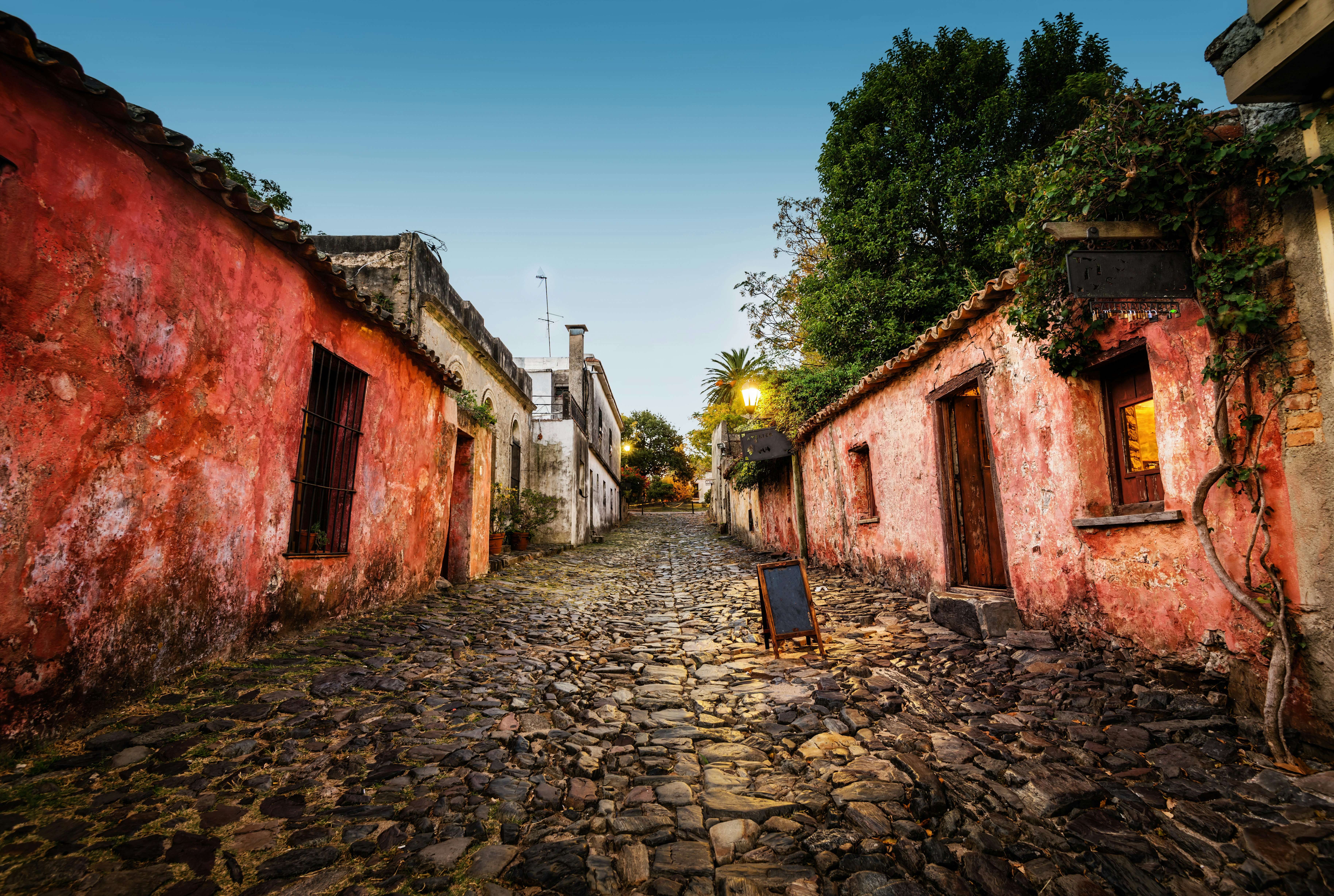 A street with large cobblestones and one-story pink stucco houses at dusk, Colonia del Sacramento, Uruguay