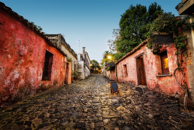 A street with large cobblestones and one-story pink stucco houses at dusk, Colonia del Sacramento, Uruguay